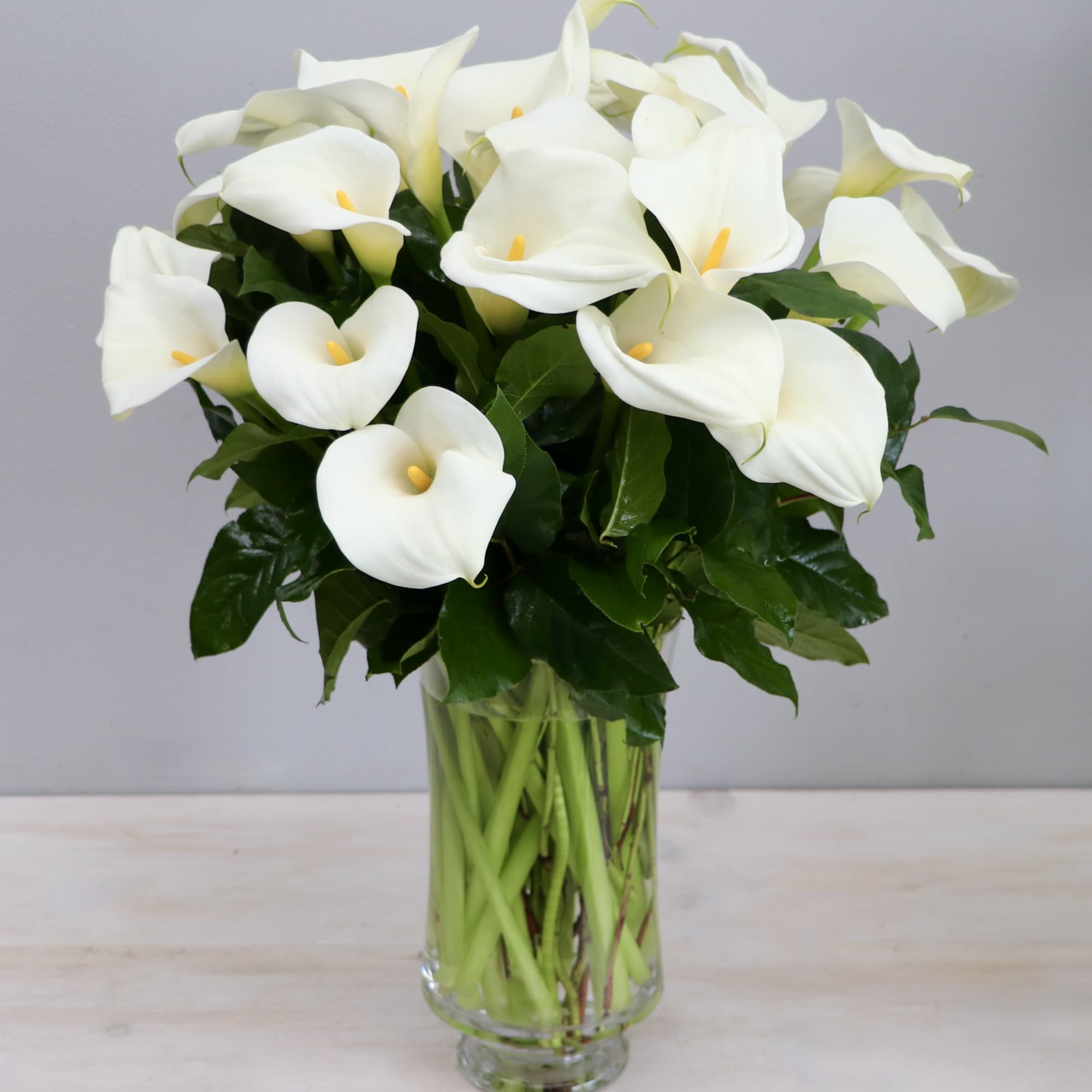 Tall arrangement of white calla lilies in a clear glass vase