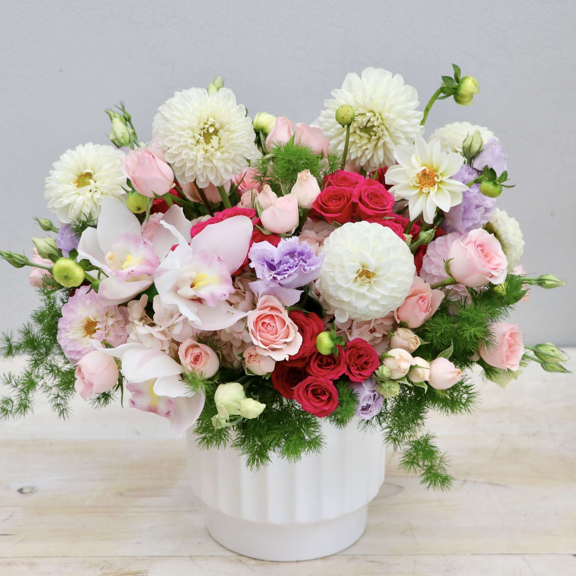 Mixed bouquet of pink, white, and red flowers in a white vase