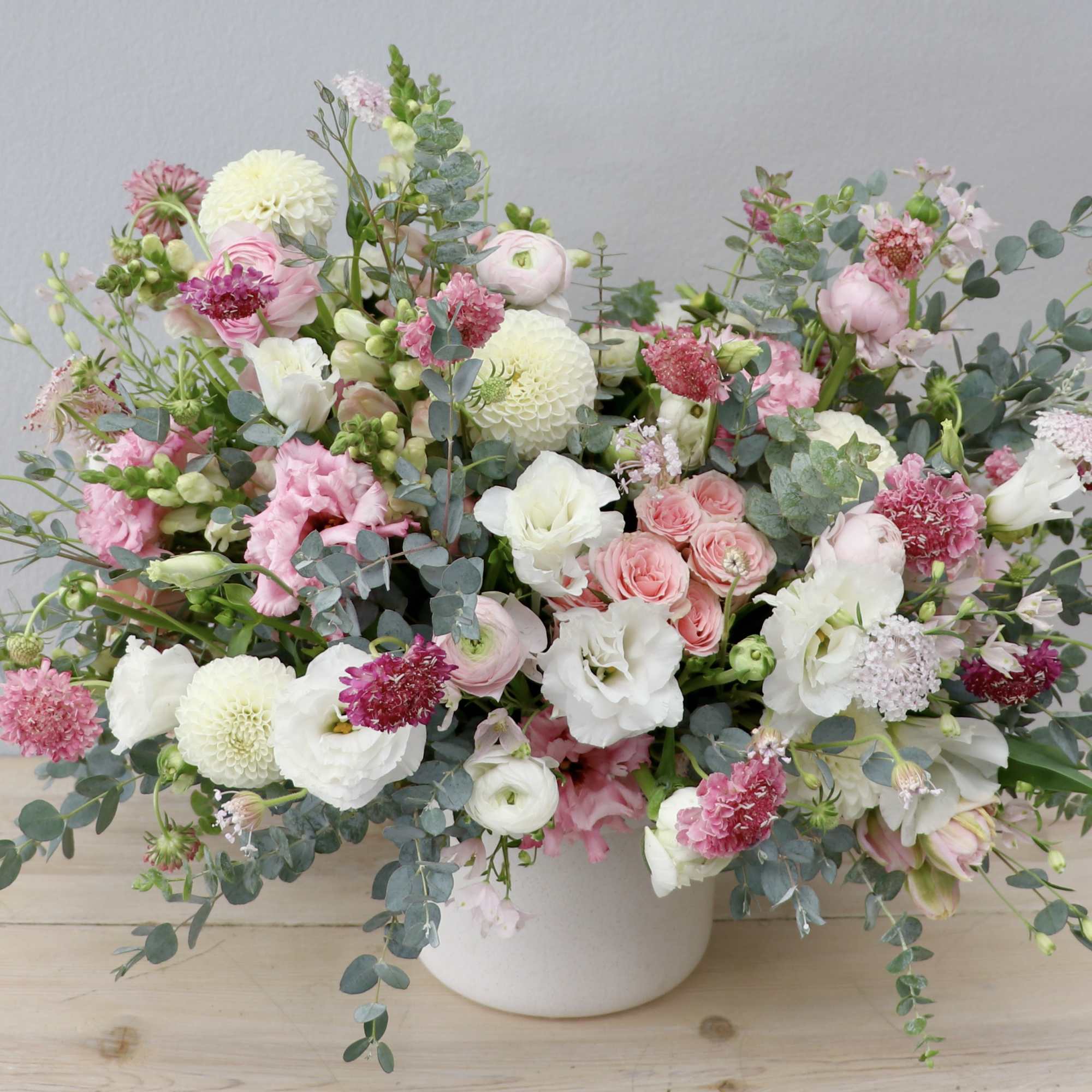 Large pink and white mixed flower arrangement in a white vase