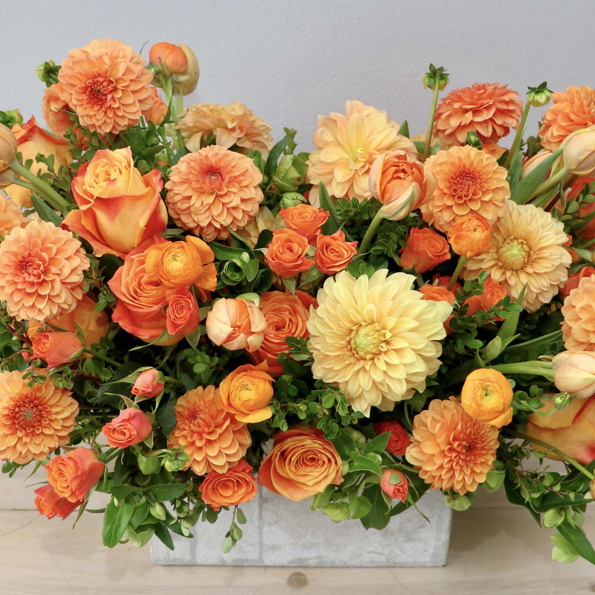 Orange and peach flowers arranged in a rectangular container