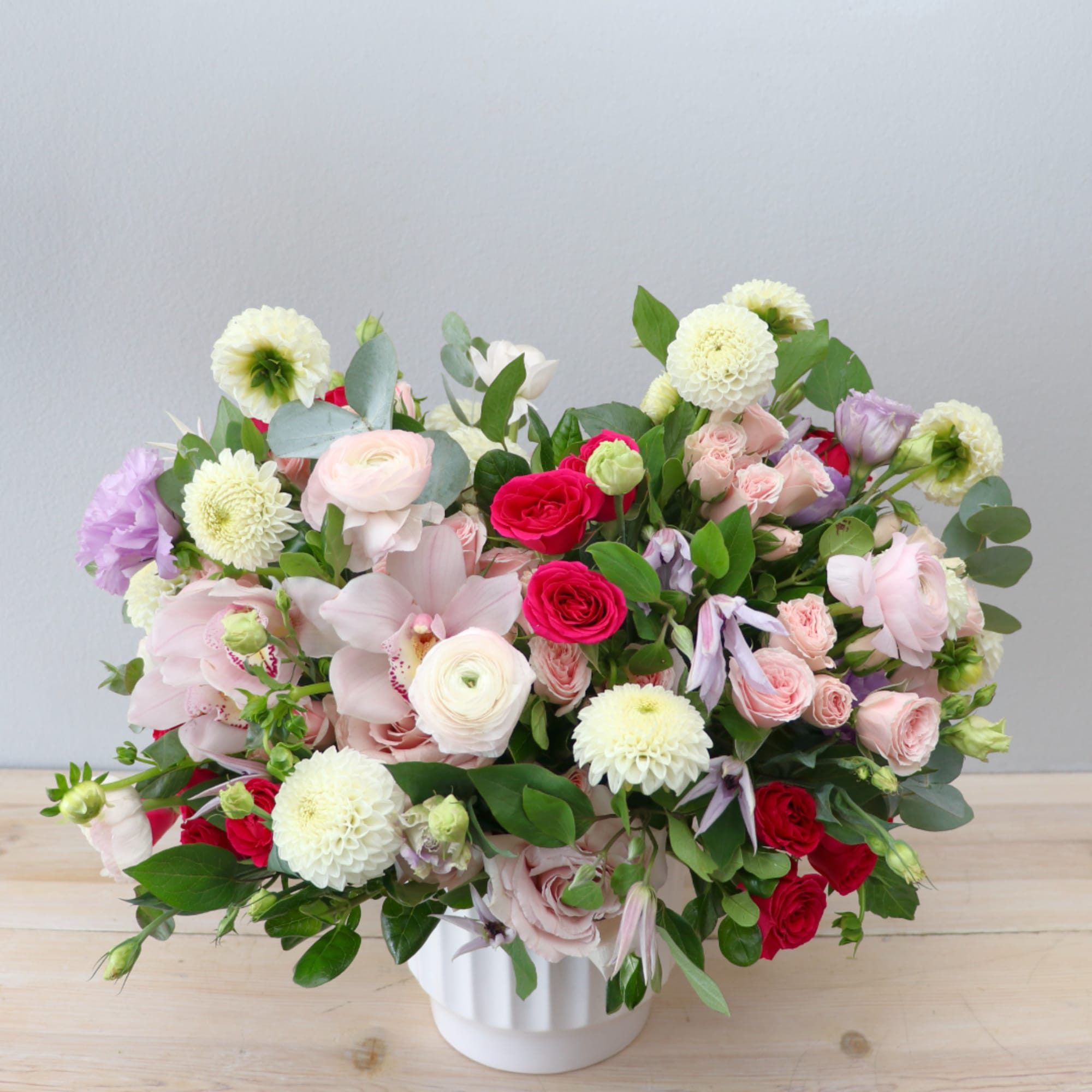 Mixed pink, white, and red flowers arranged in a white vase