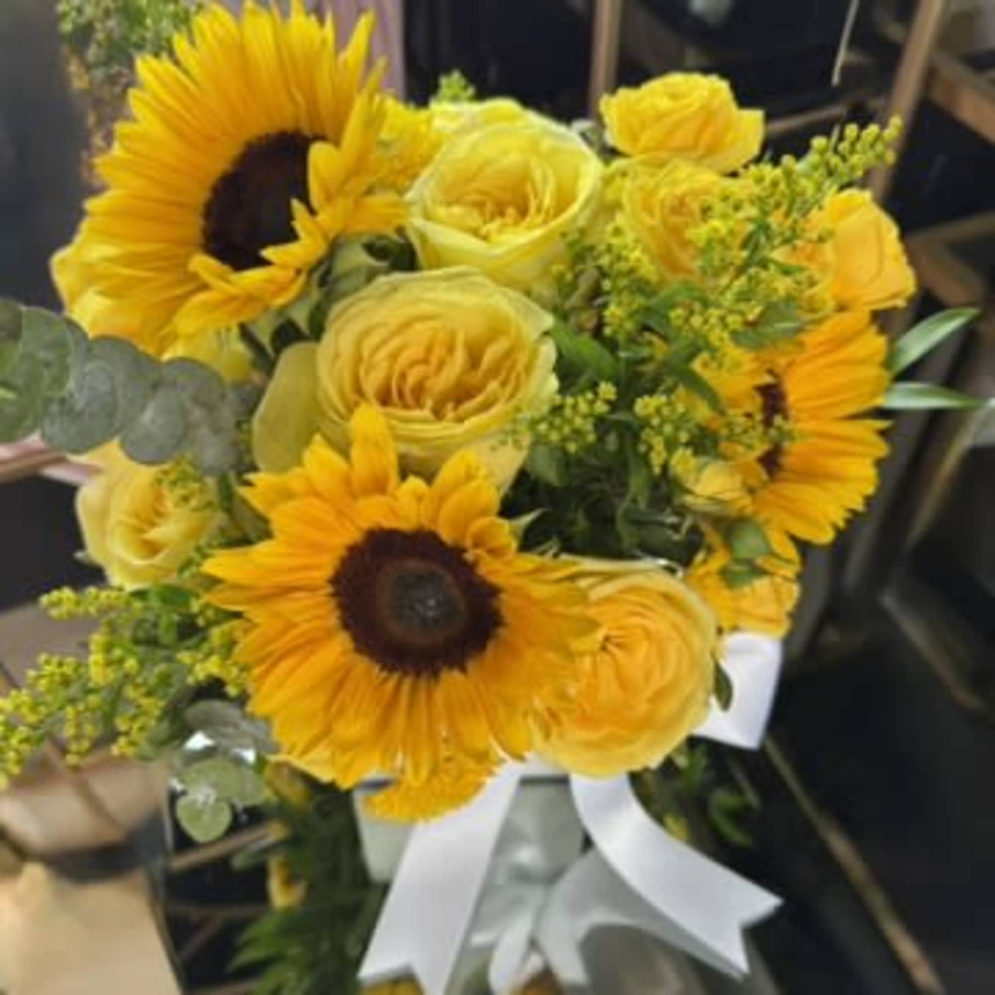 Yellow bouquet with sunflowers and roses tied with a white ribbon