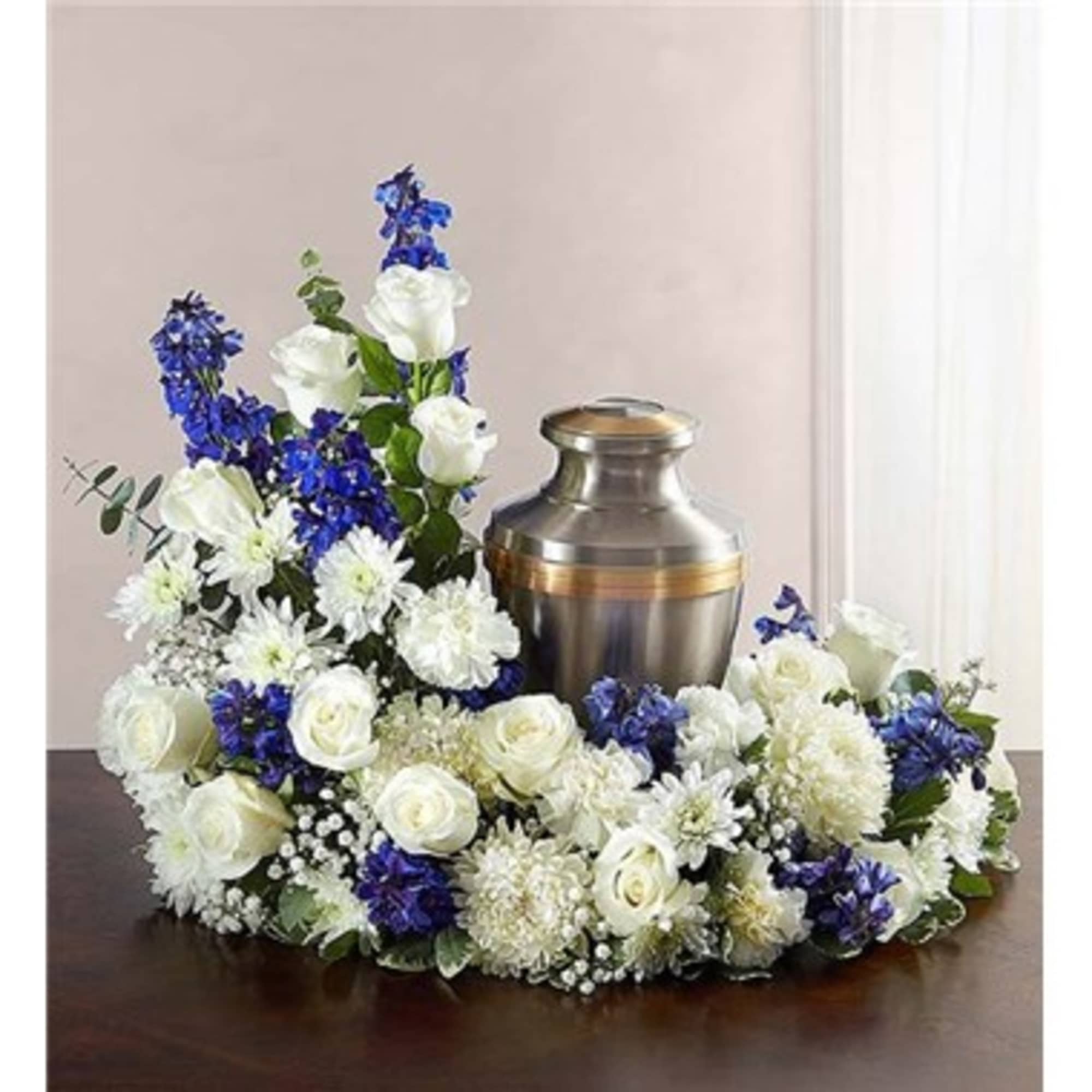 White and blue floral funeral urn arrangement on a table