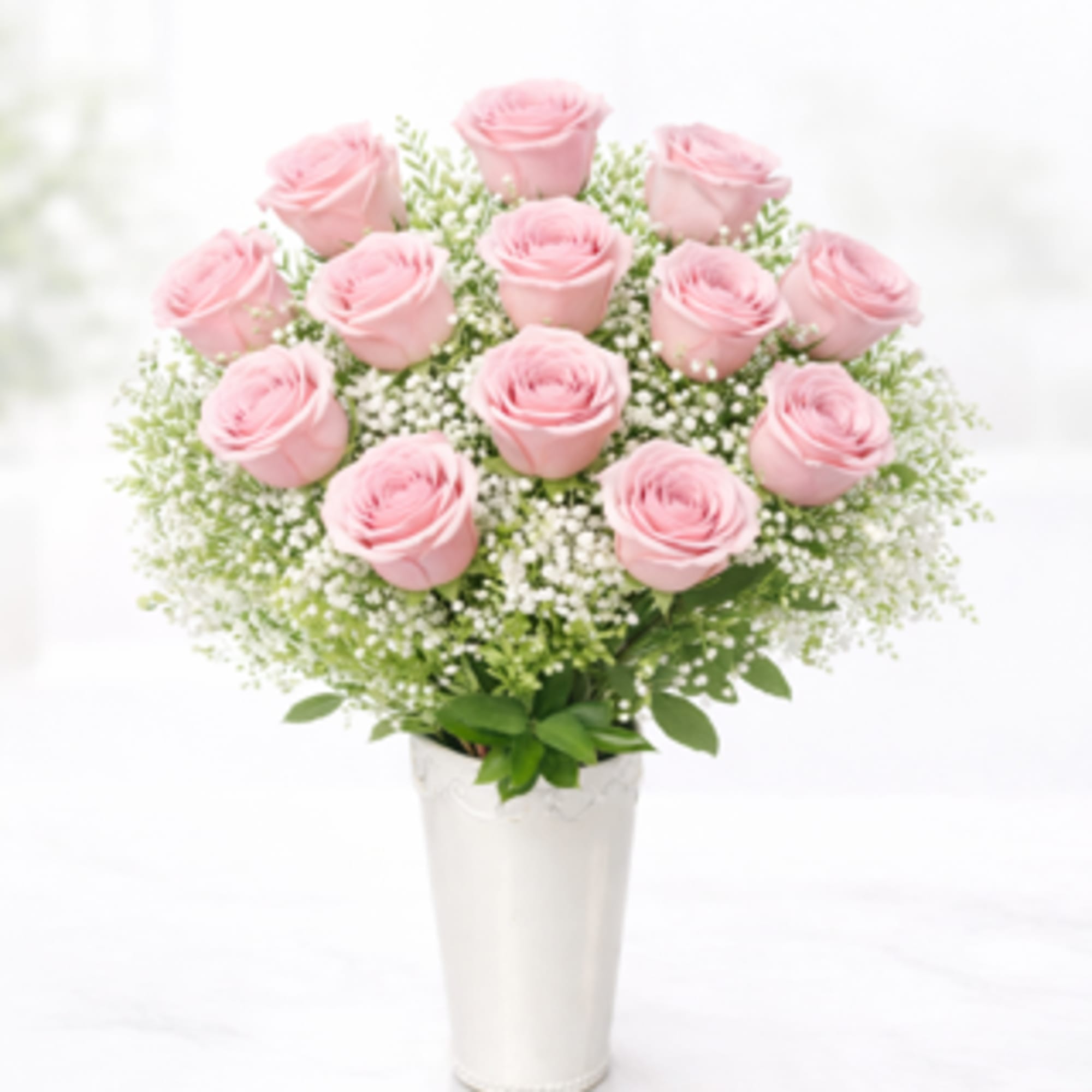 Rounded cluster of  pink roses with white filler and soft green