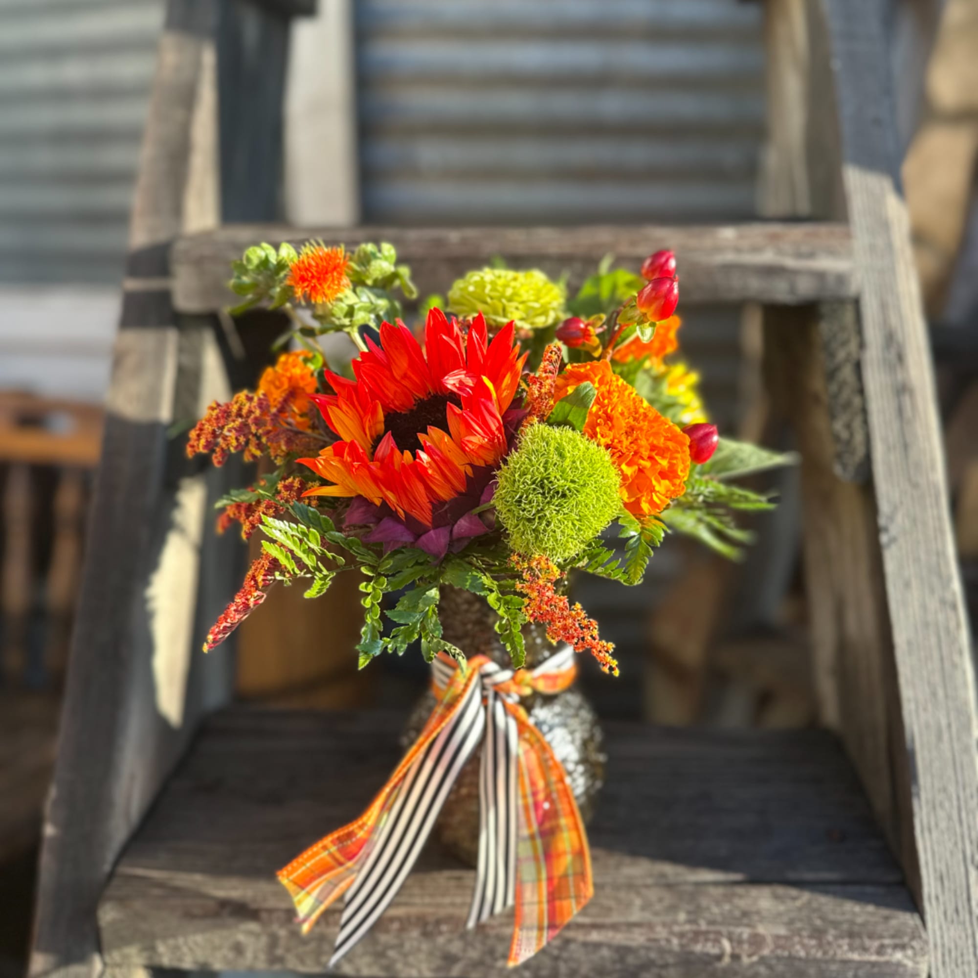 Bright mixed bouquet in a textured vase with striped ribbon