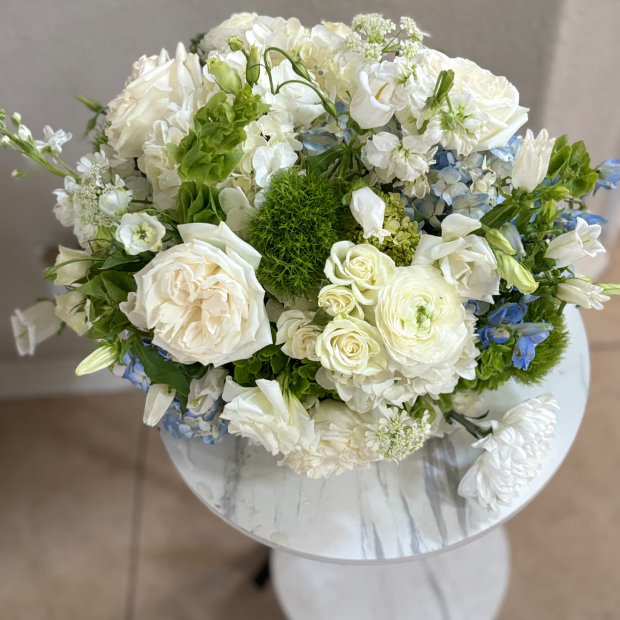 White and blue mixed bouquet in a round white vase