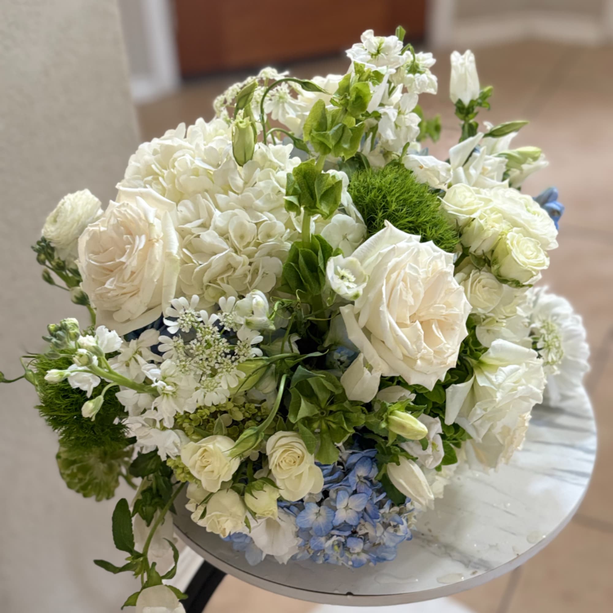 White floral bouquet with blue accents on a round table