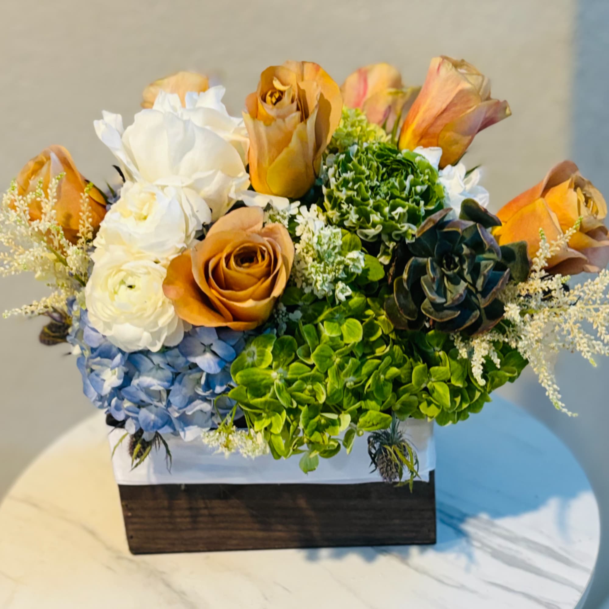 Mixed bouquet of roses, hydrangeas, and carnations in a wooden box