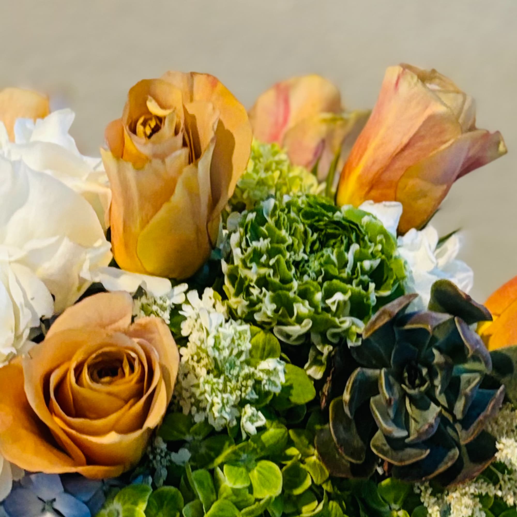 Bouquet of tan roses, white blooms, and green hydrangeas with succulents