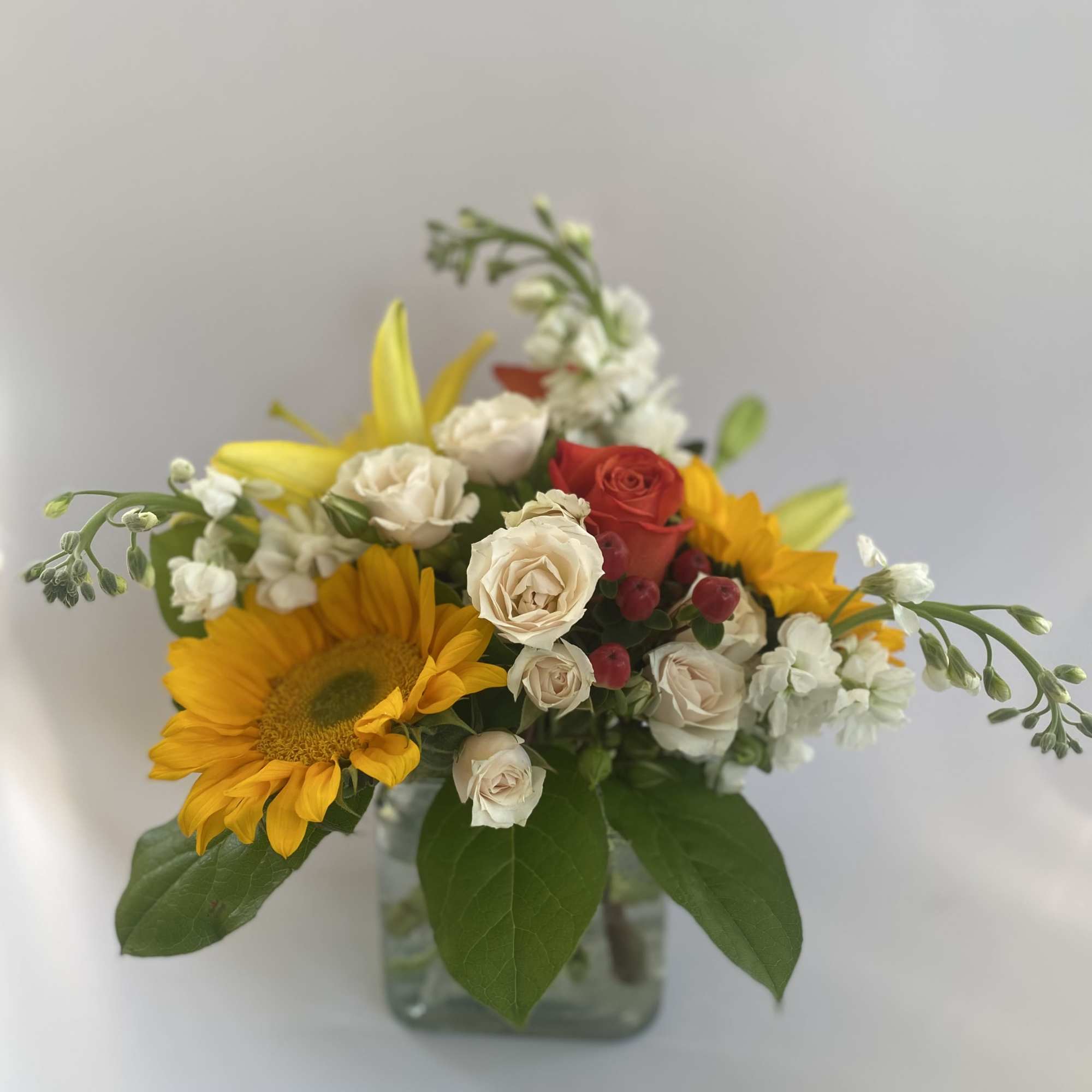 Sunflower and rose bouquet in a square glass vase