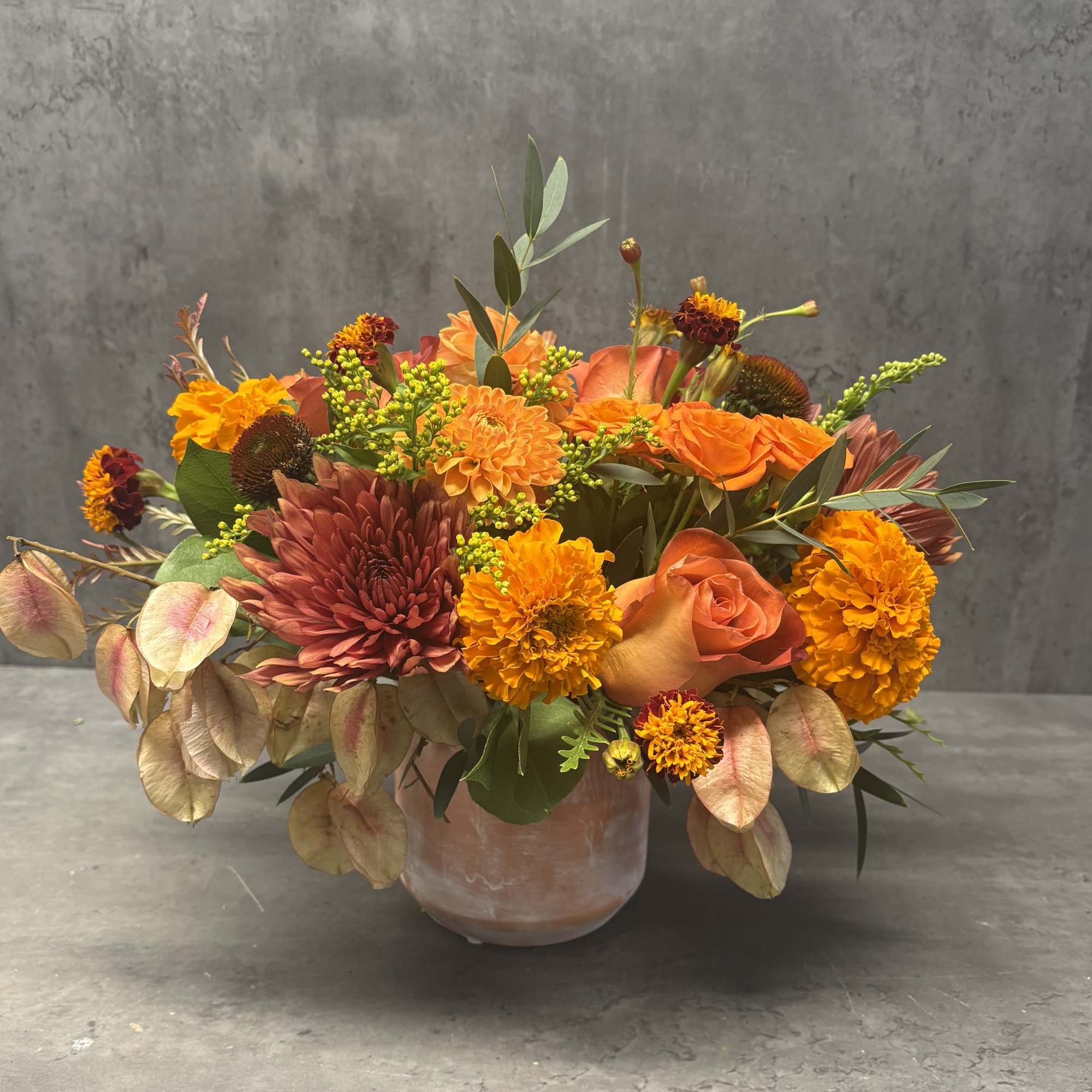 Orange and burgundy mixed bouquet in a pink vase