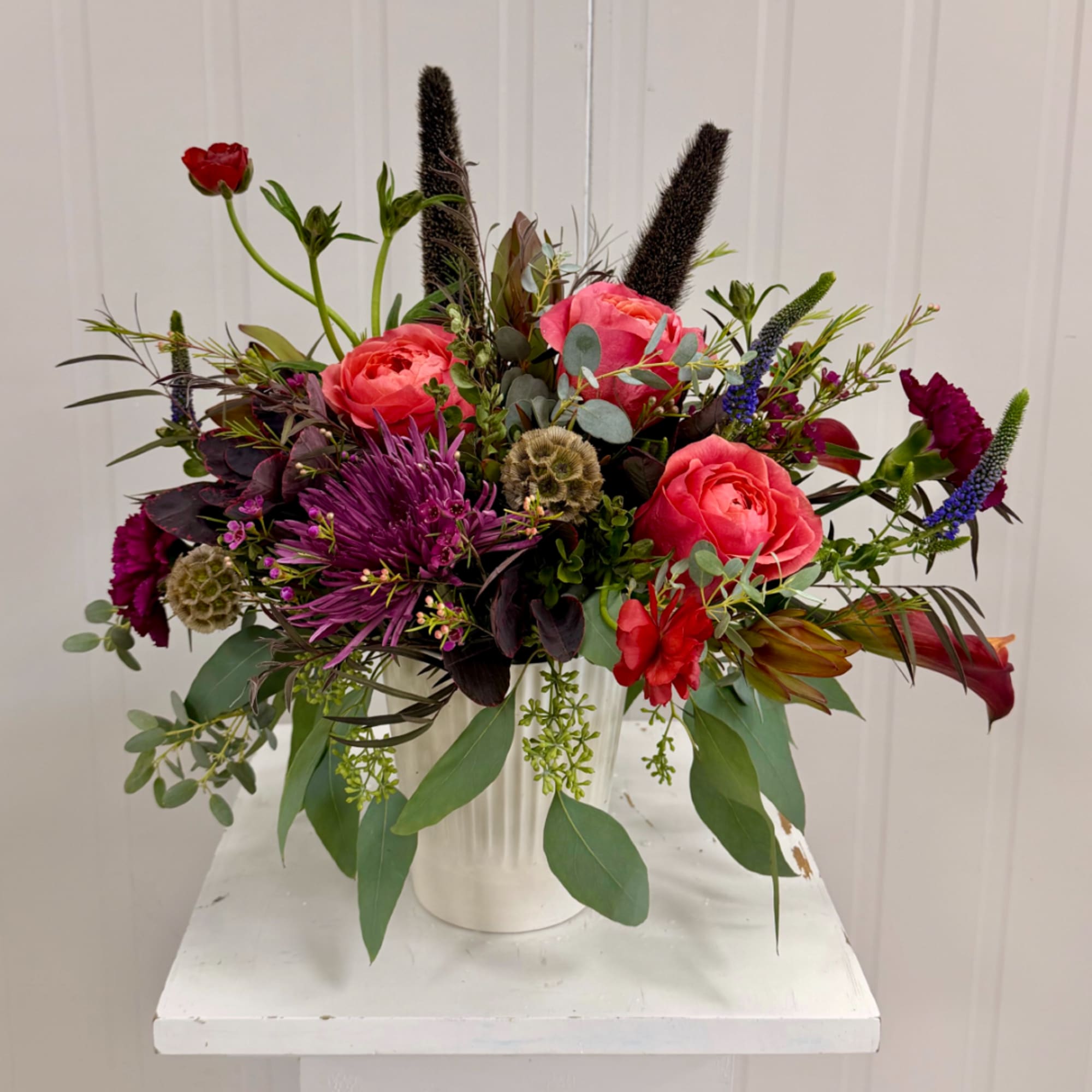 Mixed bouquet of pink roses and purple blooms in a white vase