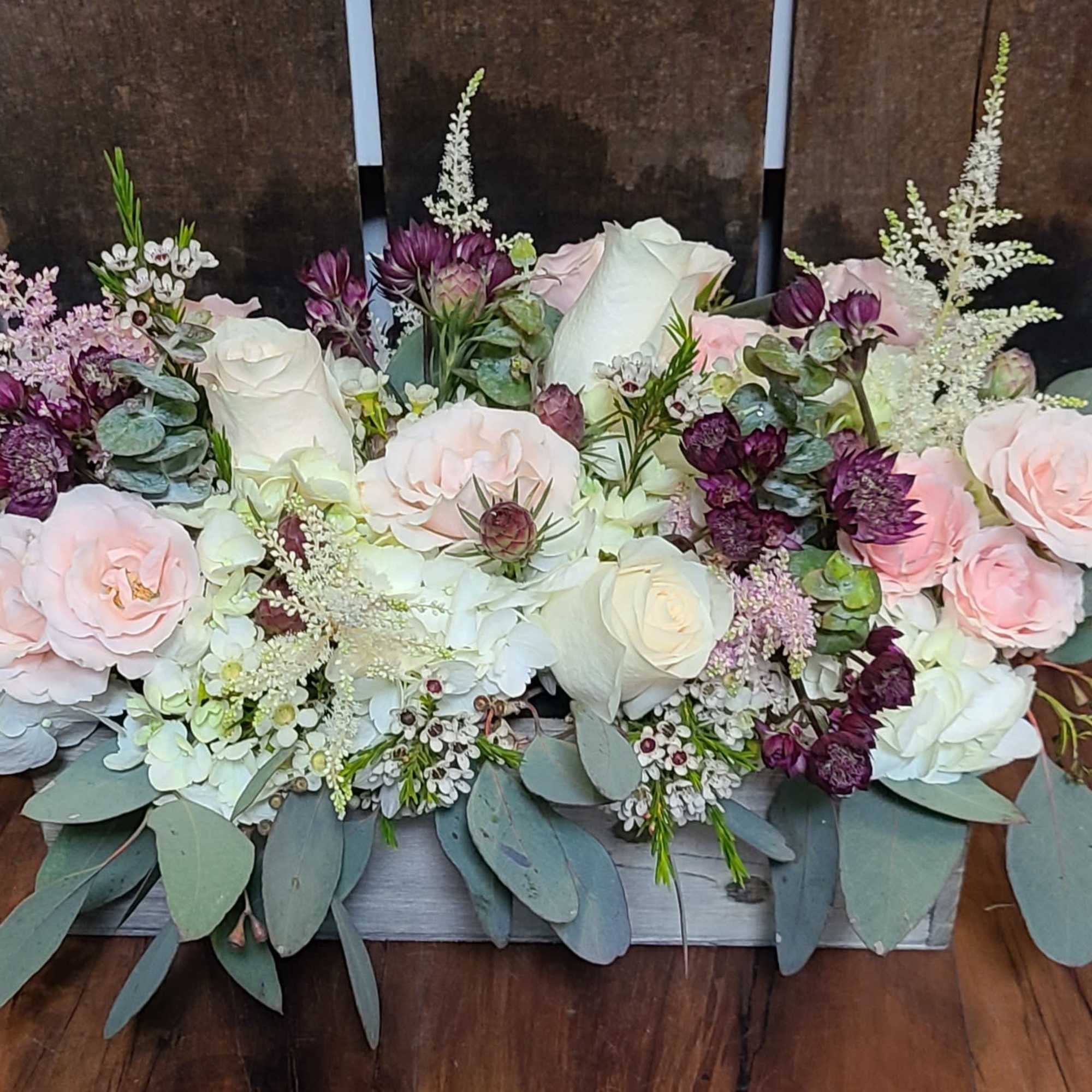 Low floral centerpiece with pink and white roses and purple blooms
