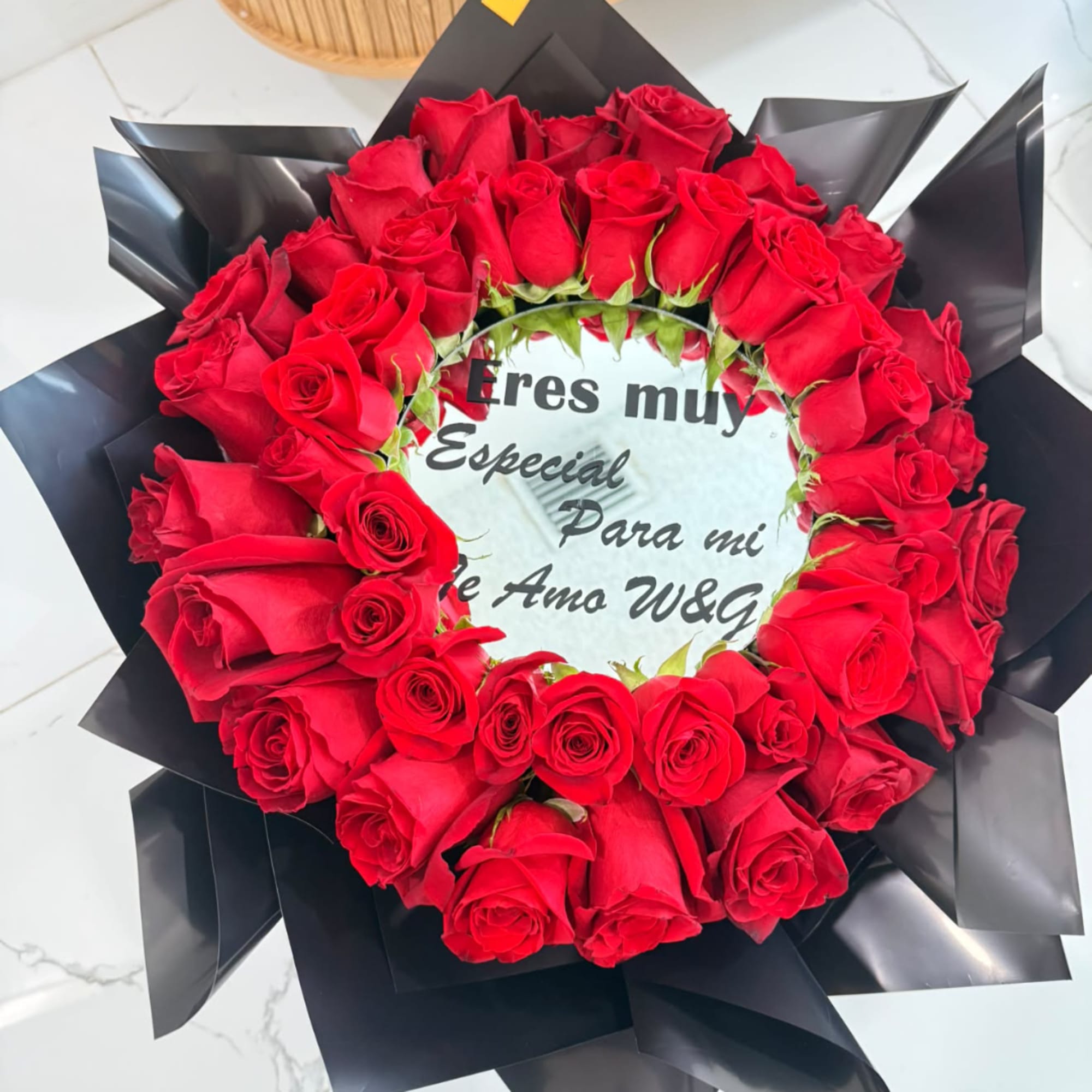 Heart-shaped red rose arrangement with a printed message in the center