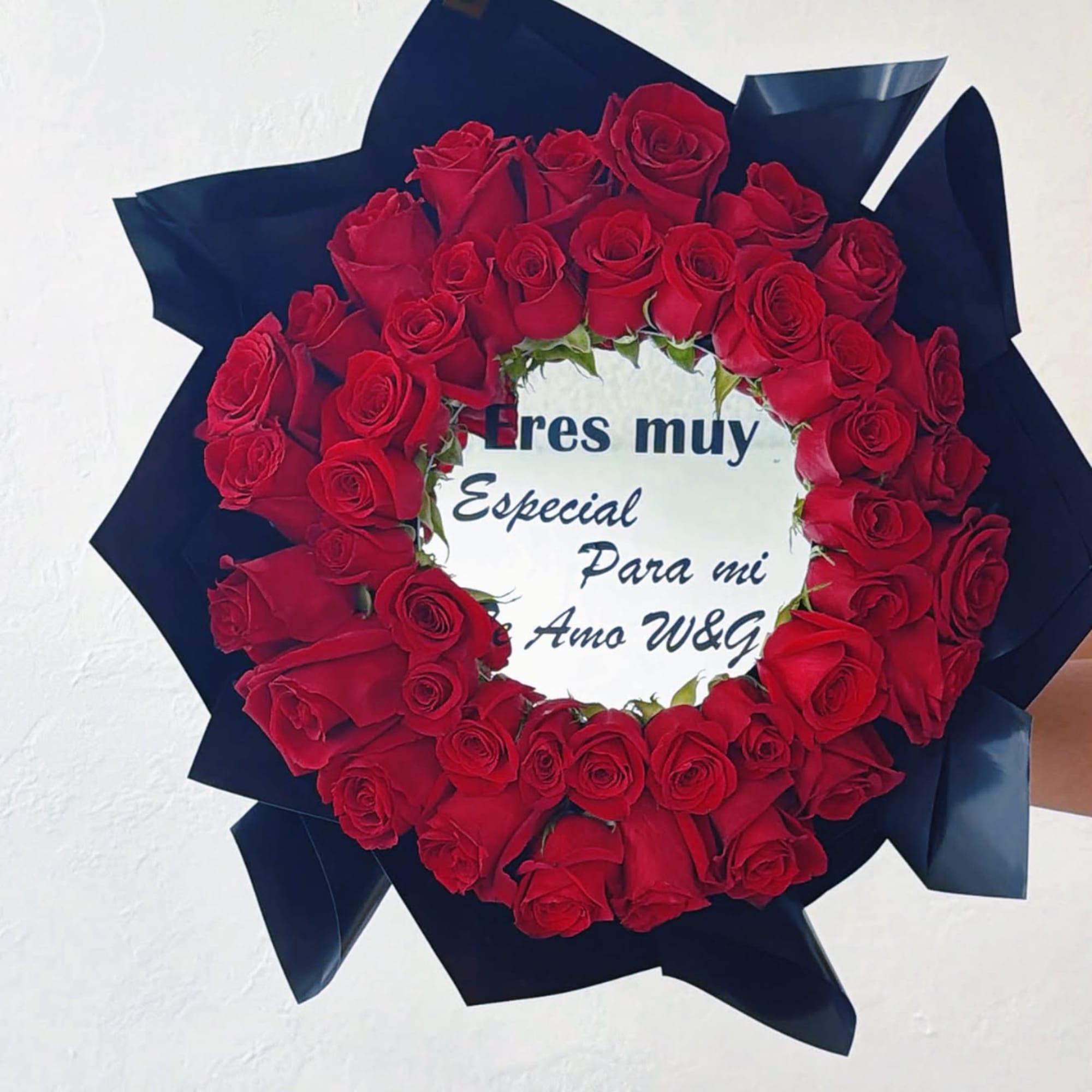 Heart-shaped bouquet of red roses with a printed message in the center