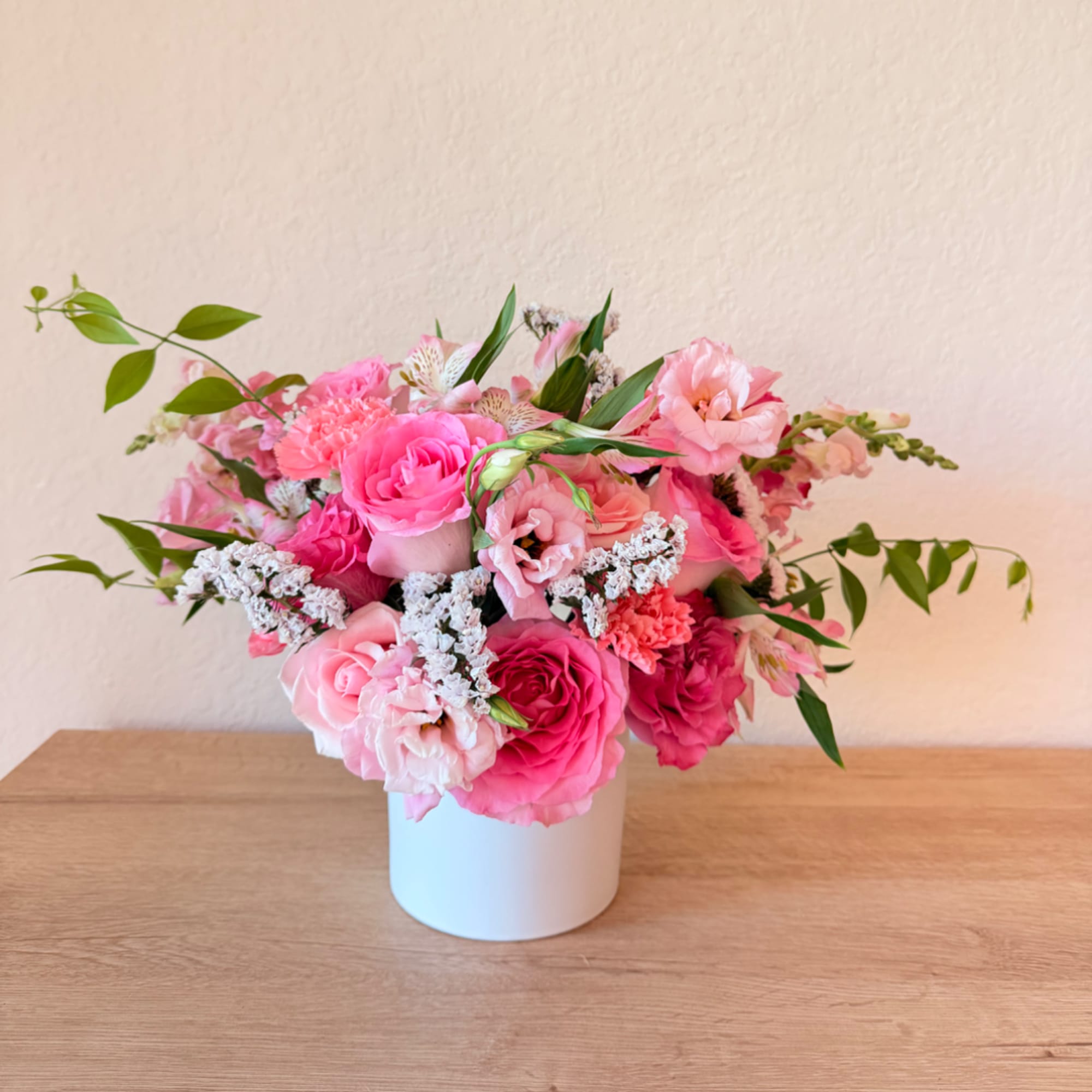 Pink mixed flower arrangement in a white vase