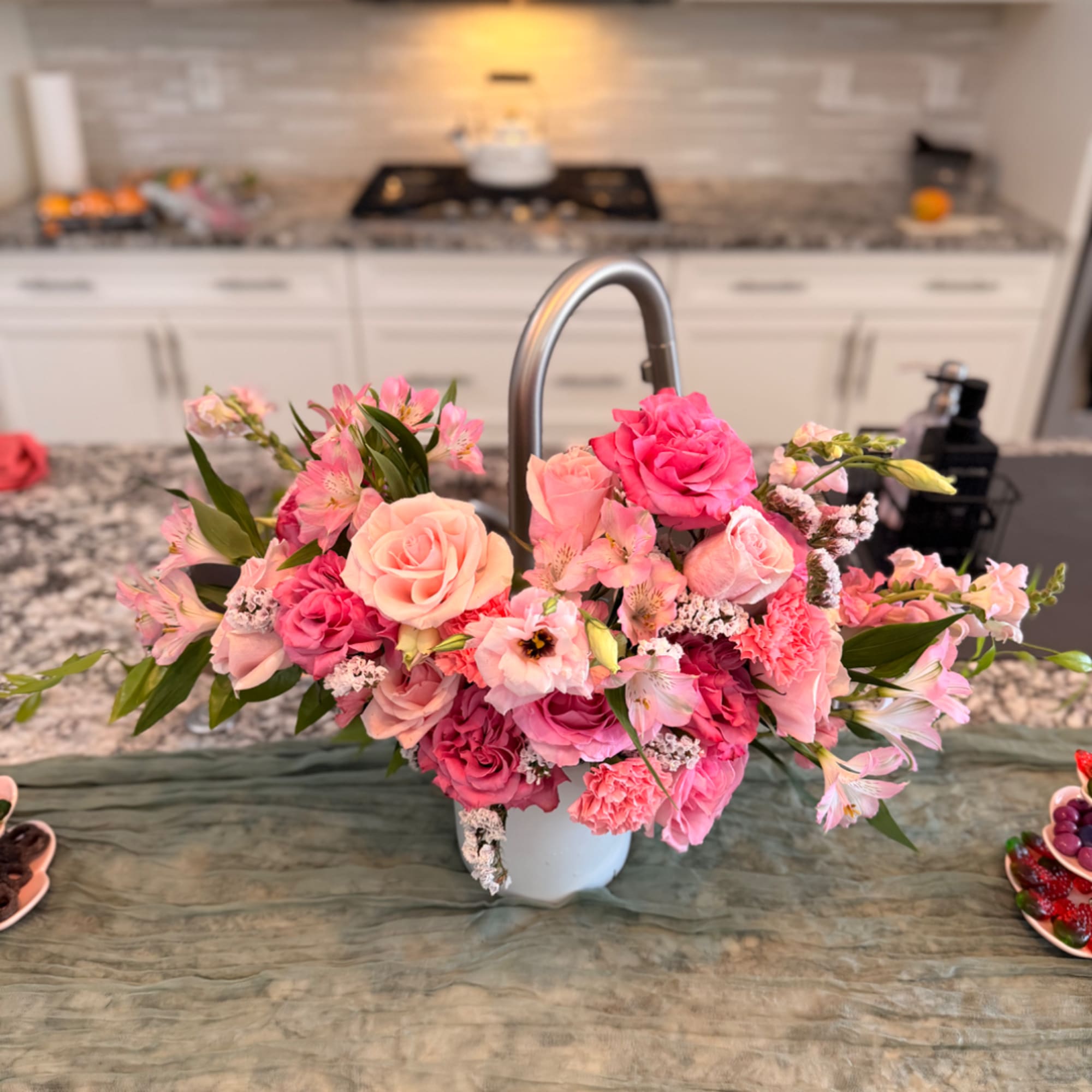 Pink and peach floral arrangement in a white vase on a kitchen counter