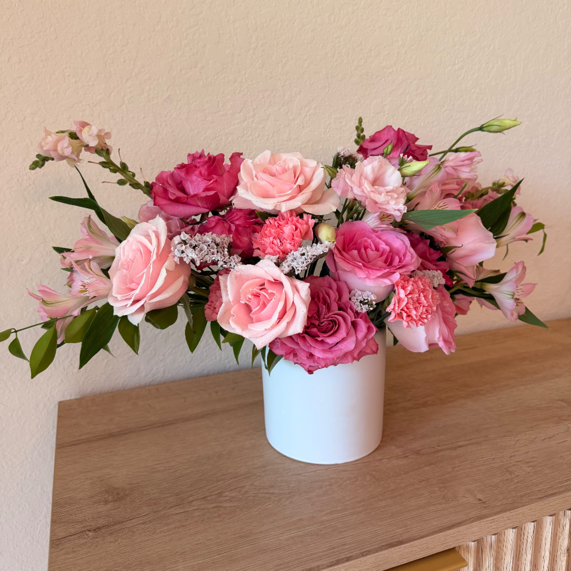 Pink and blush roses arranged in a white vase