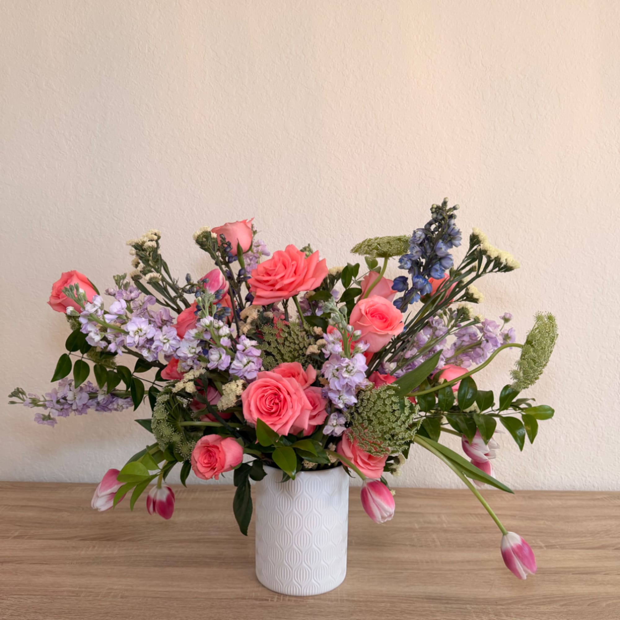 Pink roses and lavender flowers in a white vase
