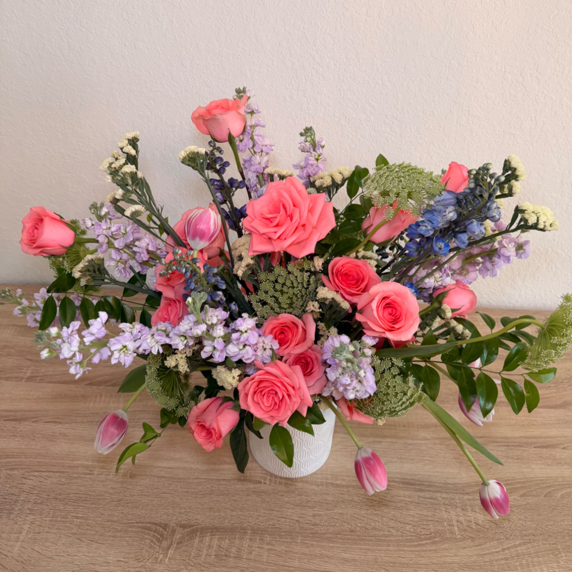 Pink roses and mixed blooms arranged in a white vase
