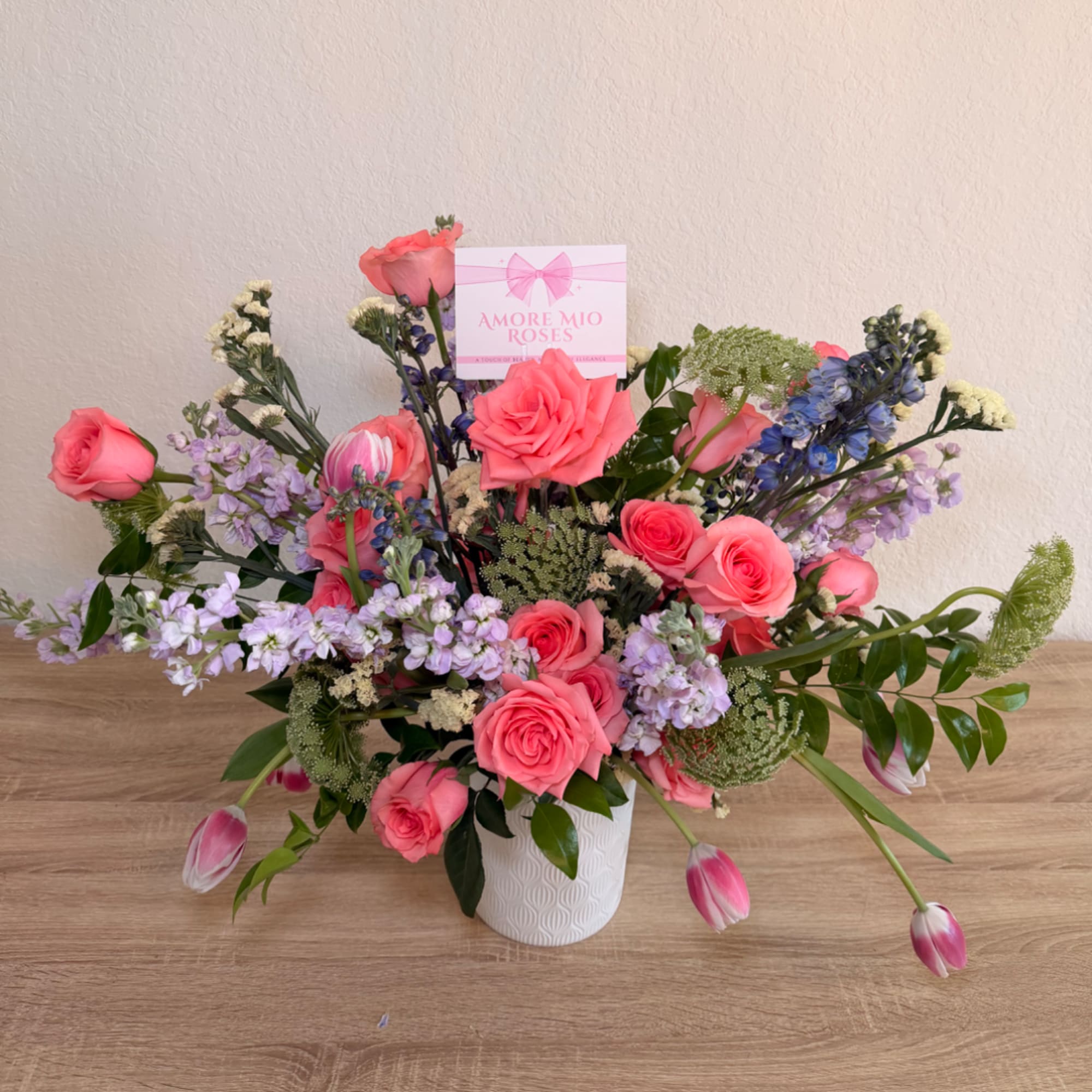 Pink roses and lavender flowers in a white vase with a gift card
