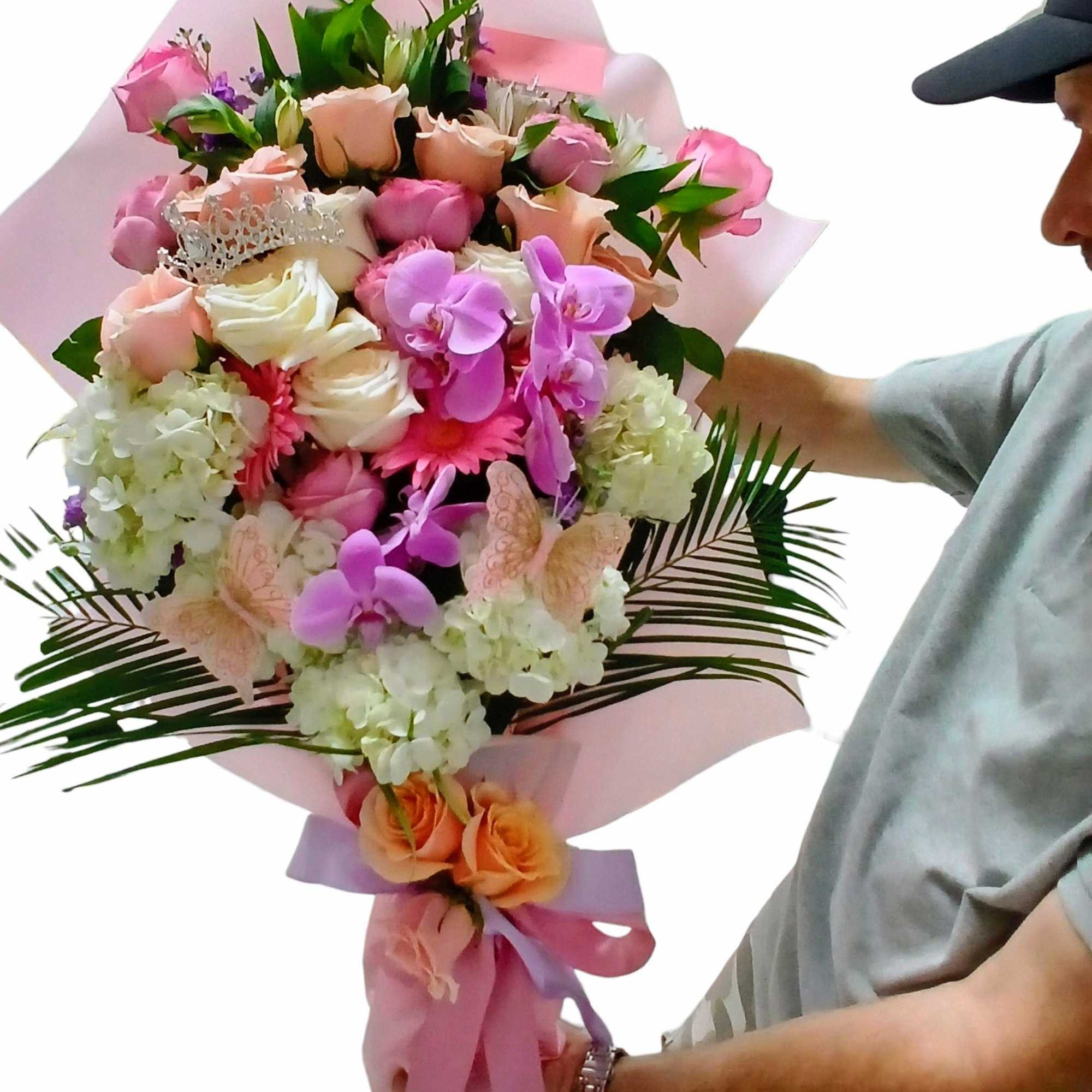 Large bouquet of pink, peach, and white flowers wrapped in pastel paper