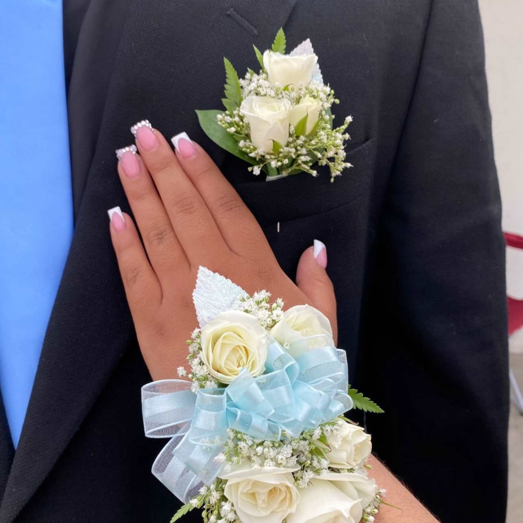White rose boutonniere and wrist corsage with blue ribbon accents