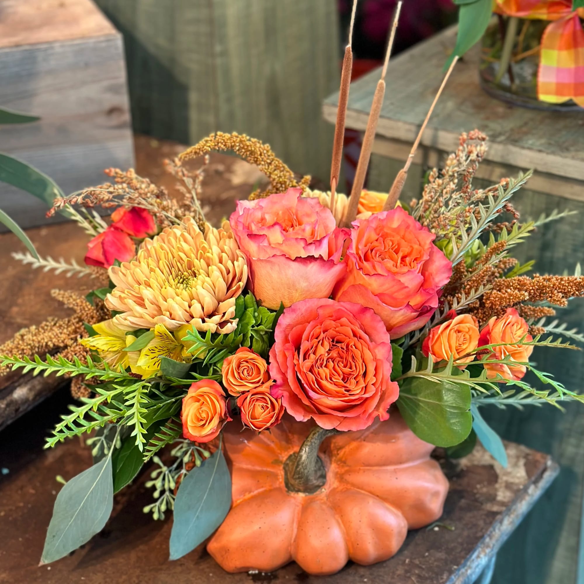 Orange and pink floral arrangement in a pumpkin-shaped container