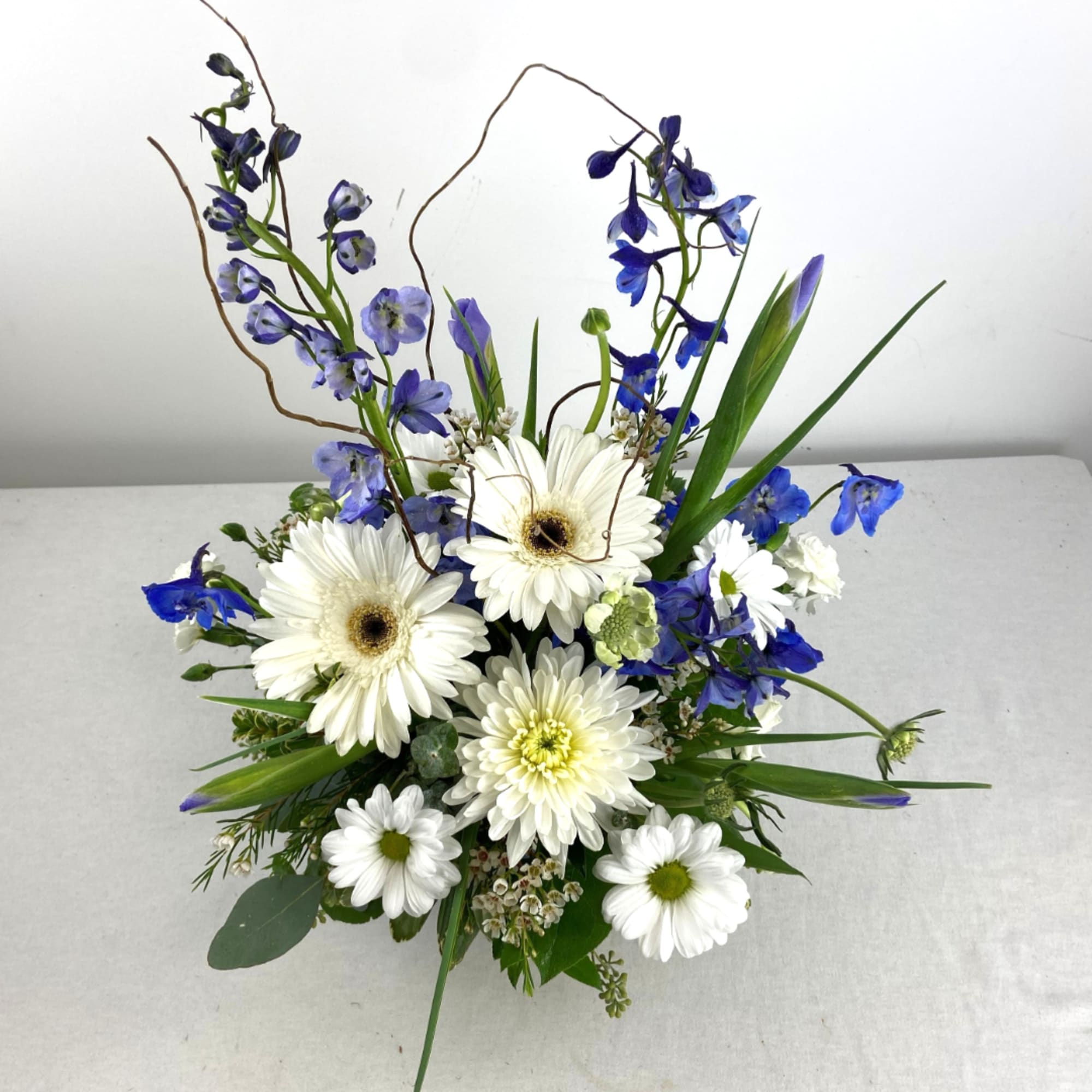 White daisies and blue flowers arranged in a low bouquet