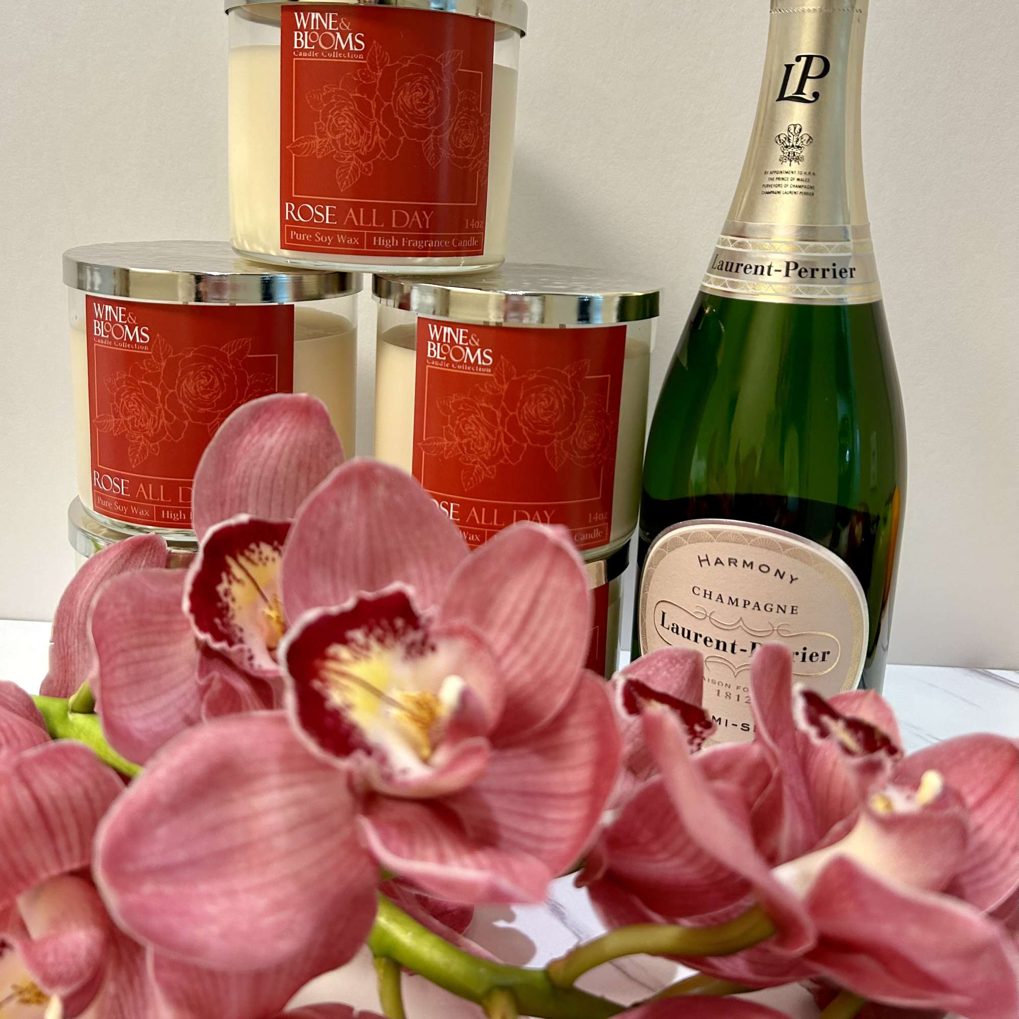 Pink orchids in front of rose-scented candles and a champagne bottle