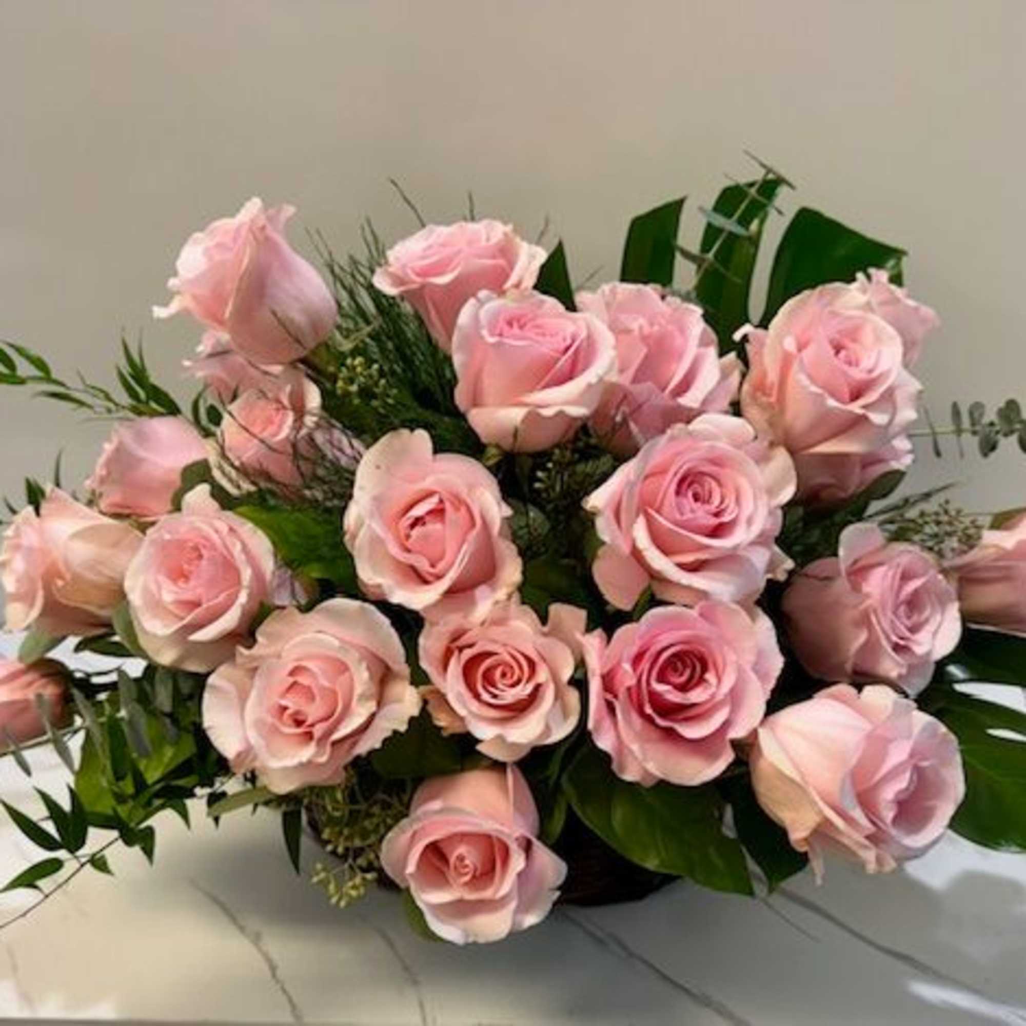 Arrangement of pale pink roses with greenery in a low container