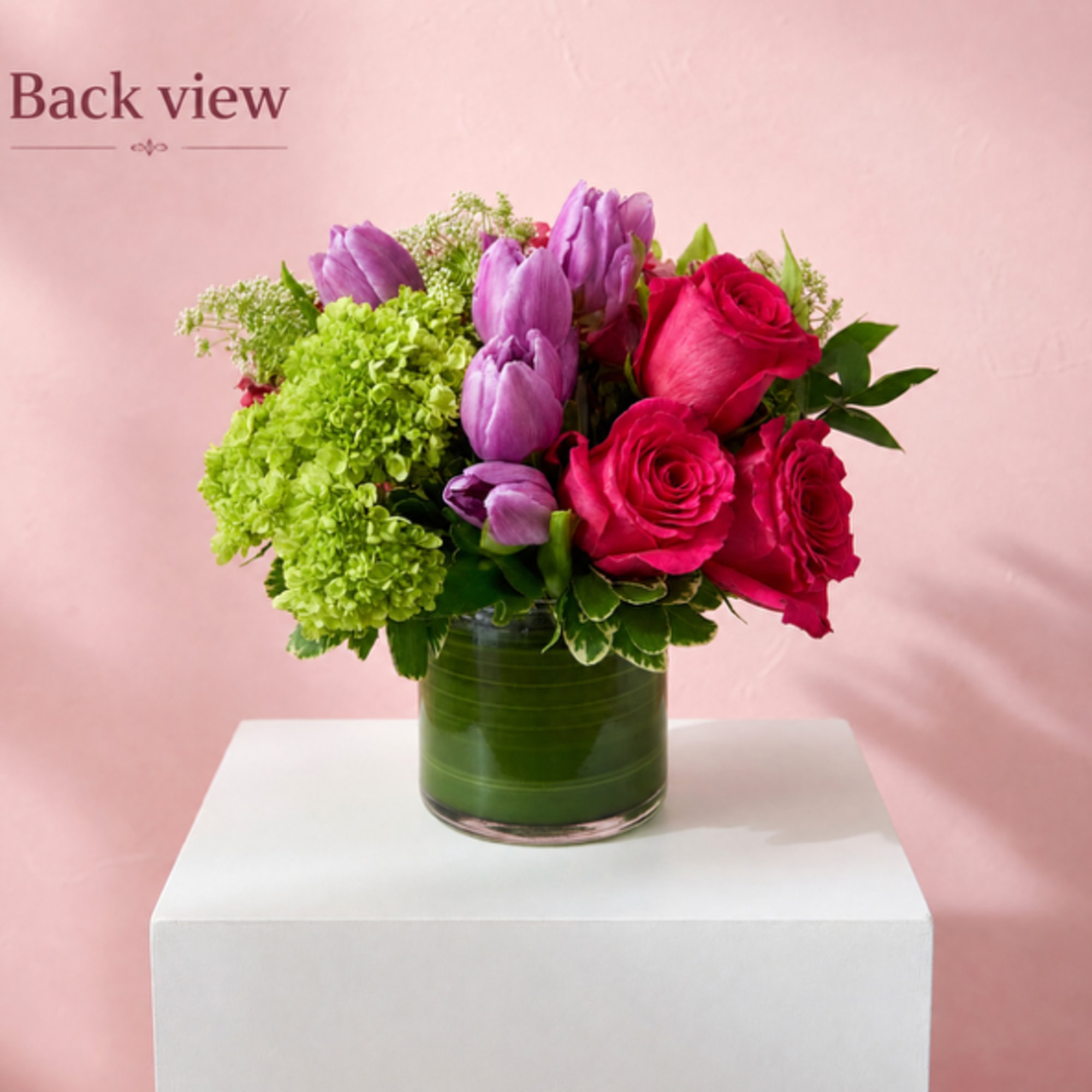 Pink roses and purple tulips arranged in a glass vase