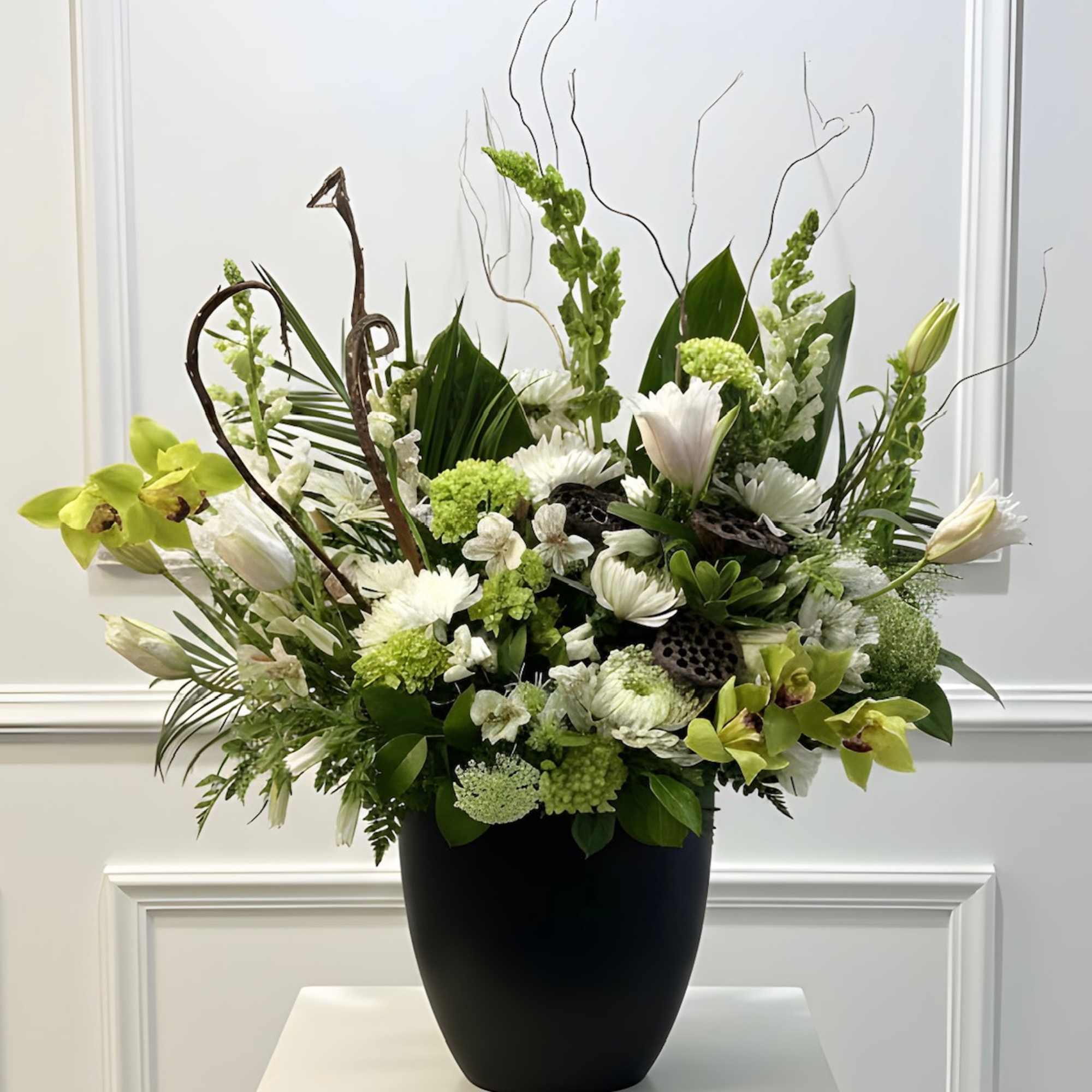 White and green floral arrangement in a black vase