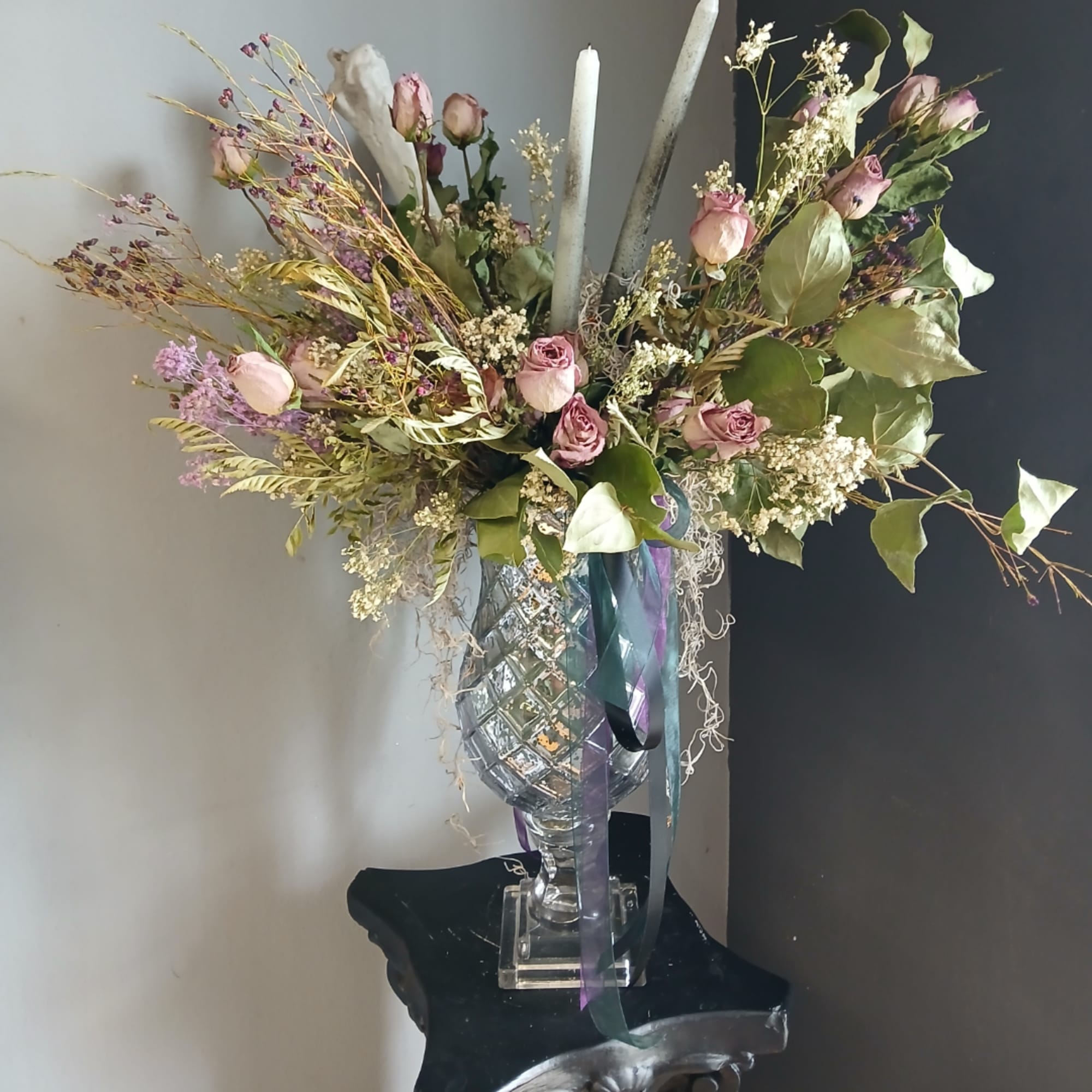 Pink roses in a clear vase with tall candles and ribbon accents