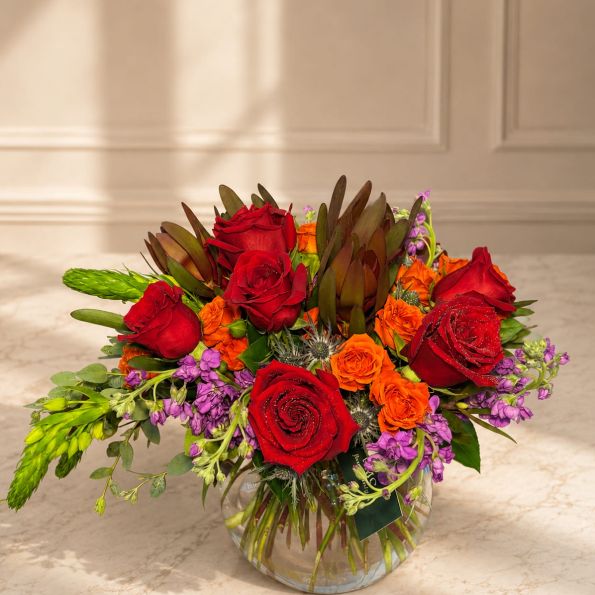 Red and orange rose bouquet in a clear glass vase