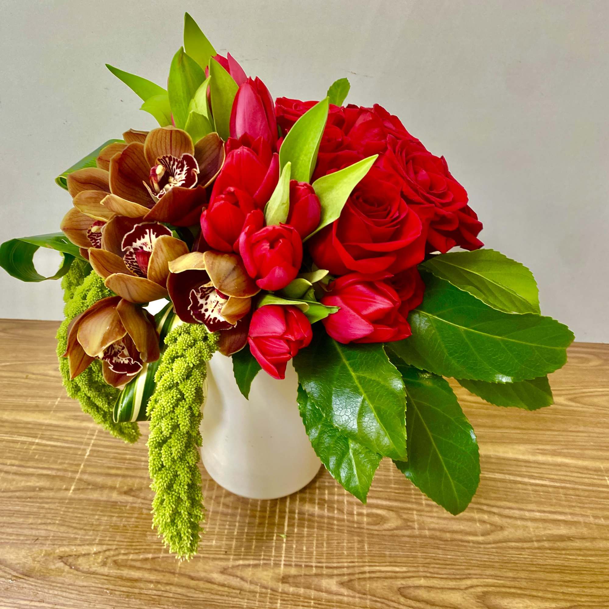 Bouquet of red roses and brown orchids in a white vase