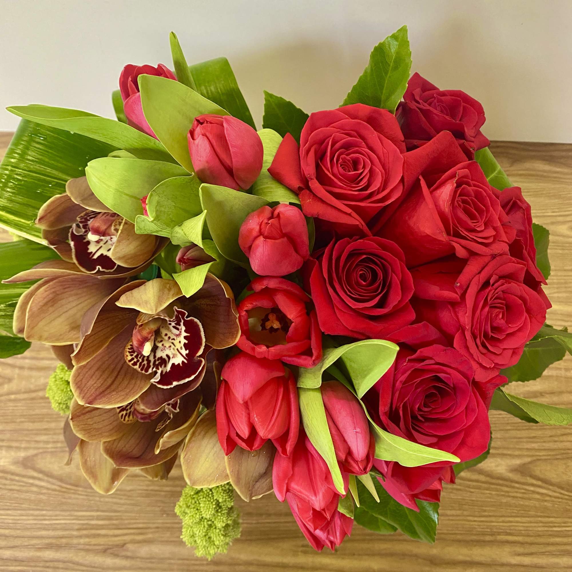 Bouquet of red roses, red tulips, and brown orchids