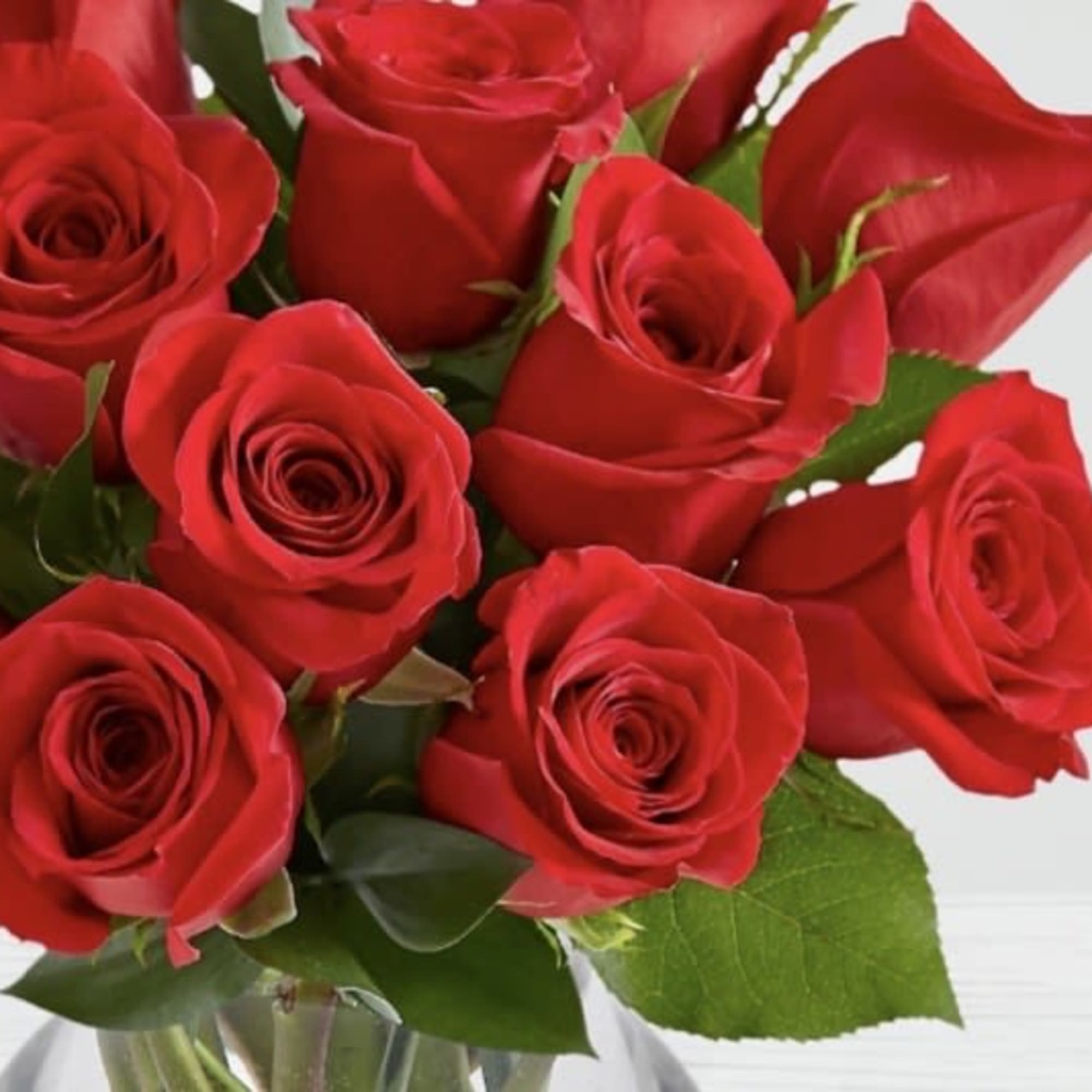 Arrangement of red roses in a clear glass vase on a light surface