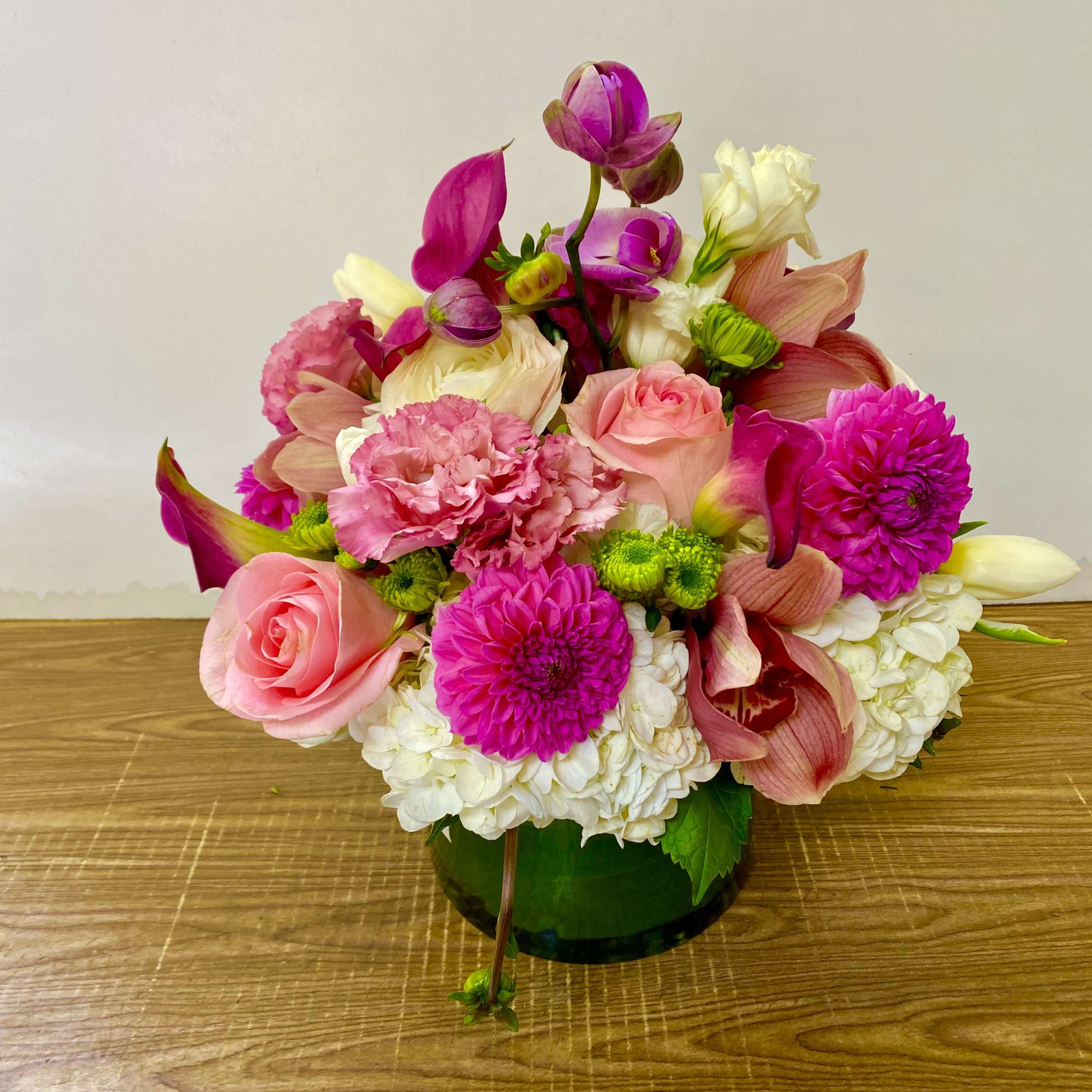Pink and white mixed flower arrangement in a green glass vase