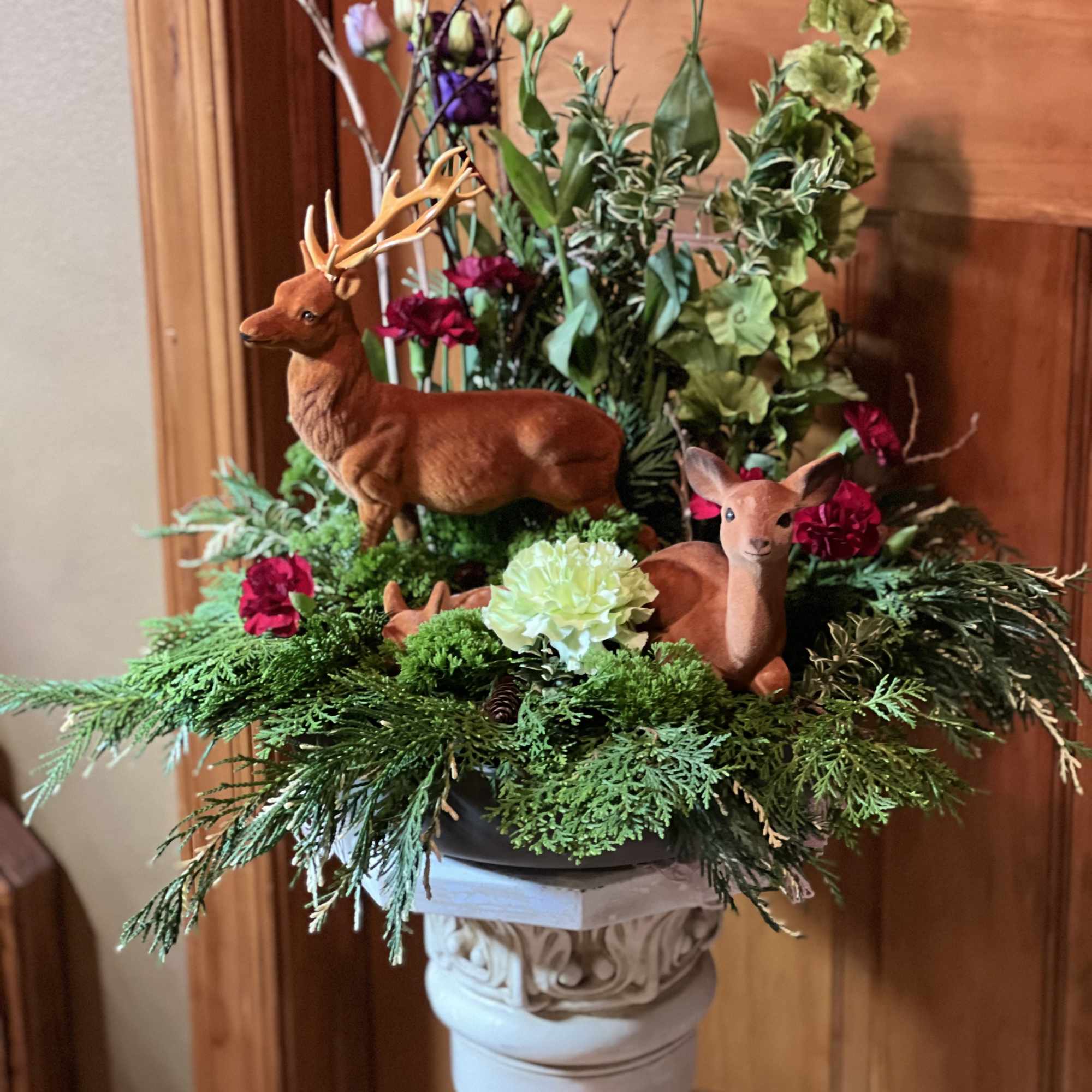 Floral arrangement with deer figurines in a pedestal container