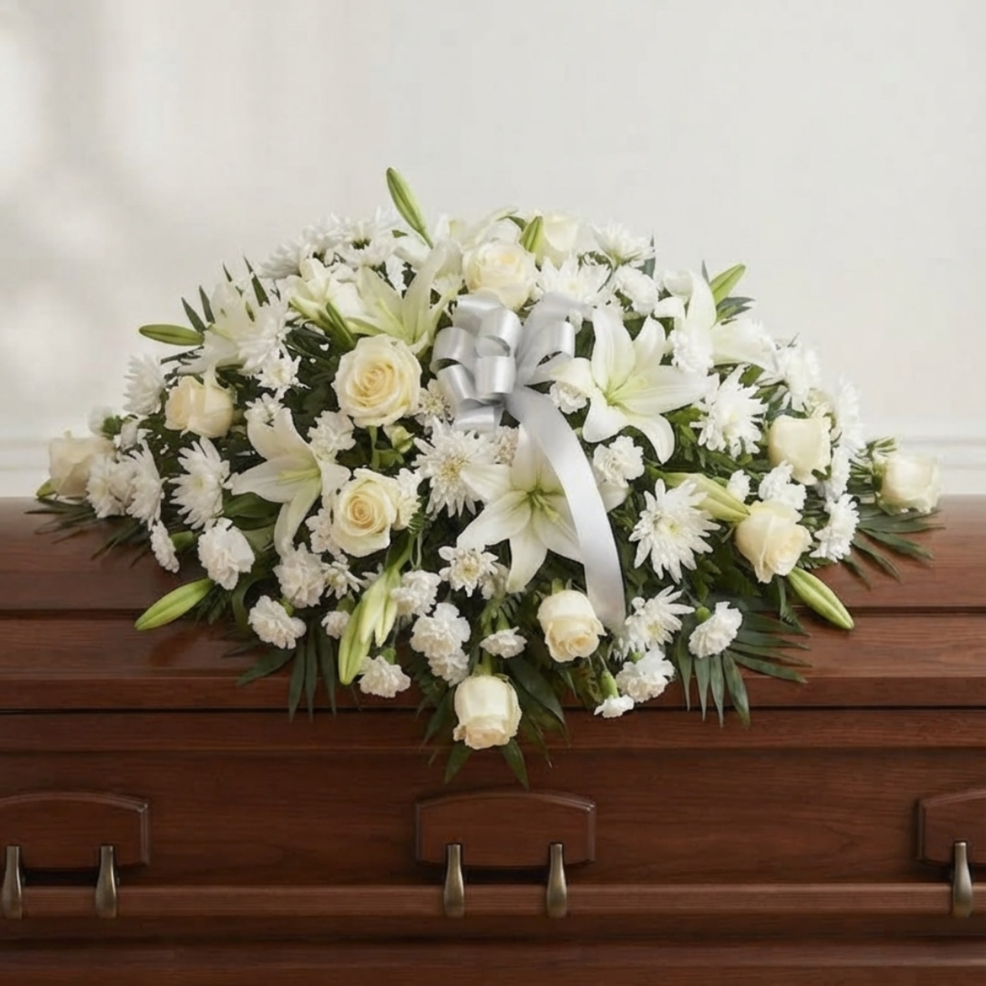 White floral casket spray with roses and lilies