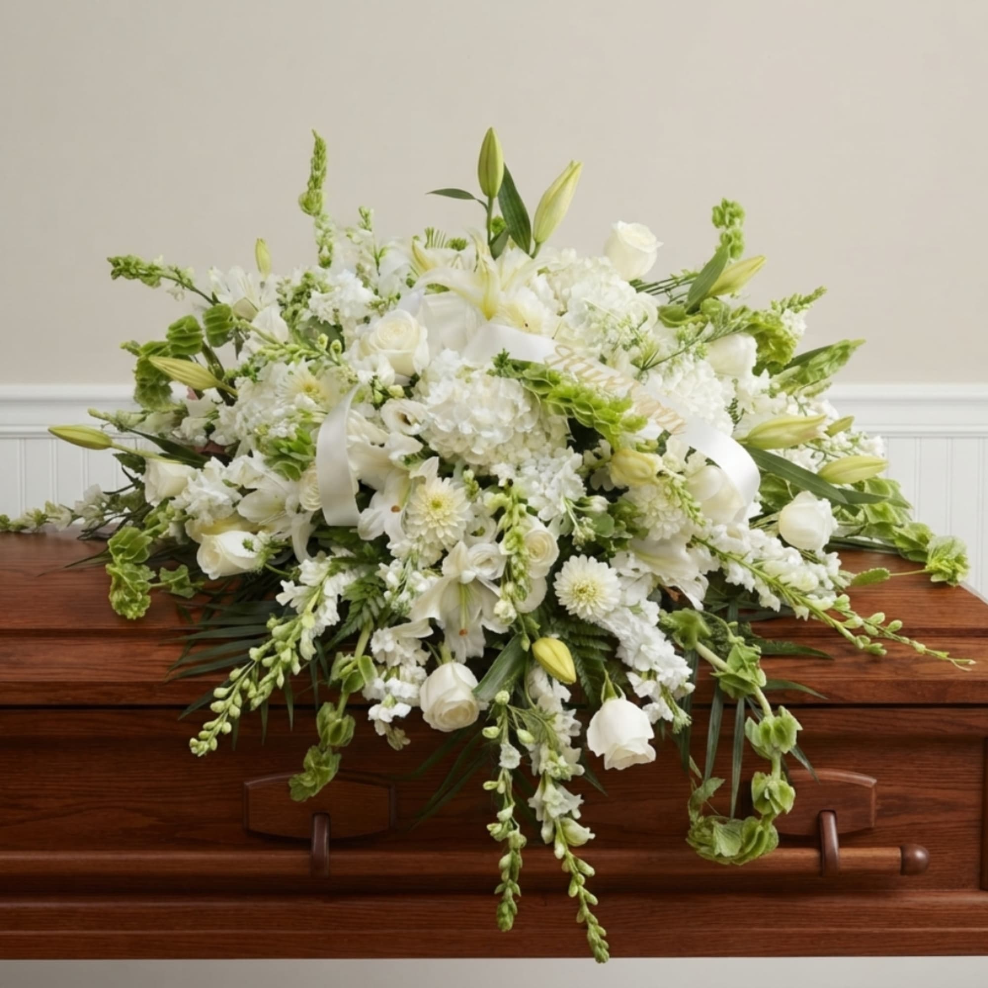 White floral casket spray with lilies and roses