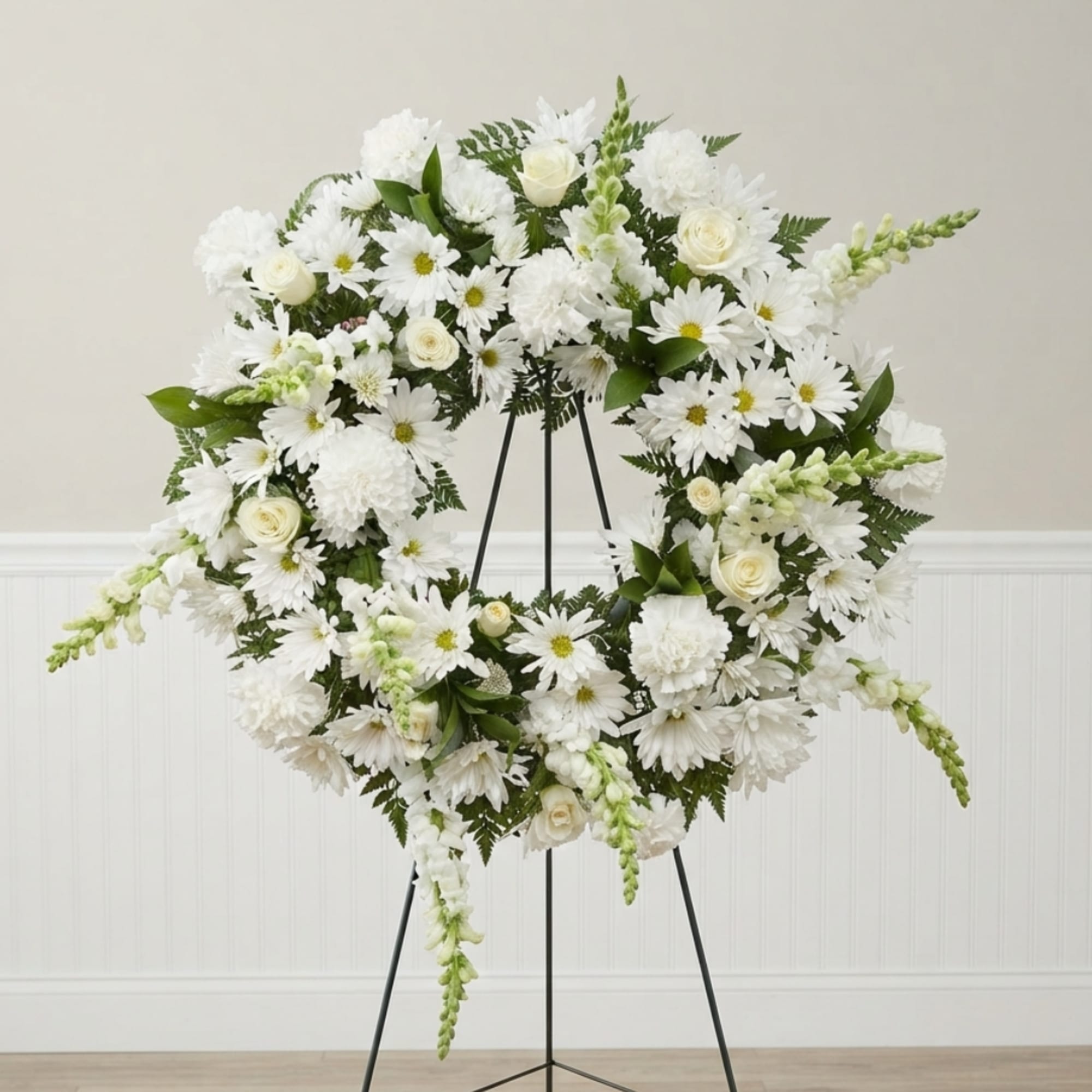 White floral wreath on a black easel stand