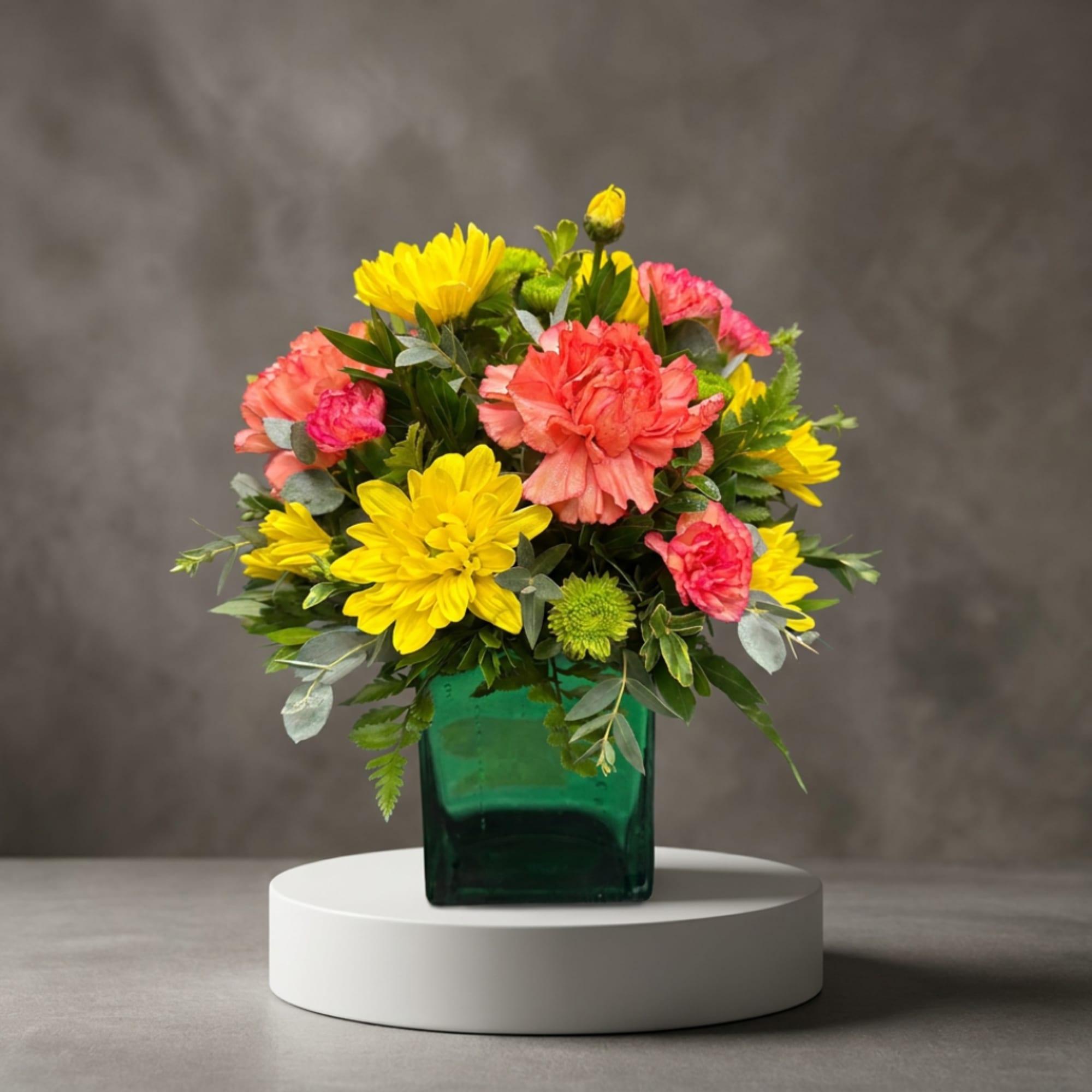 Yellow and pink mixed bouquet in a green glass vase