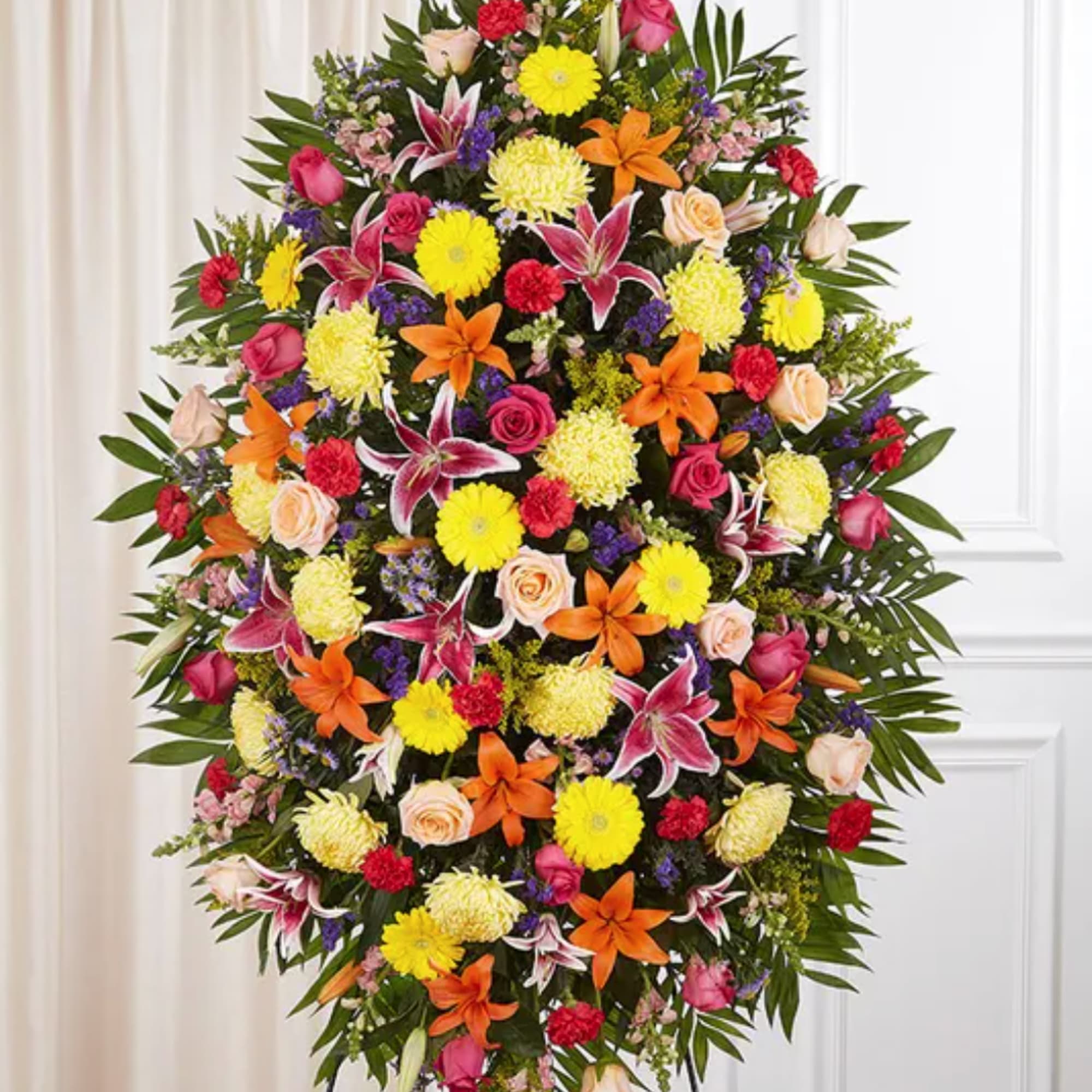 Large standing floral spray with bright mixed flowers on a black easel