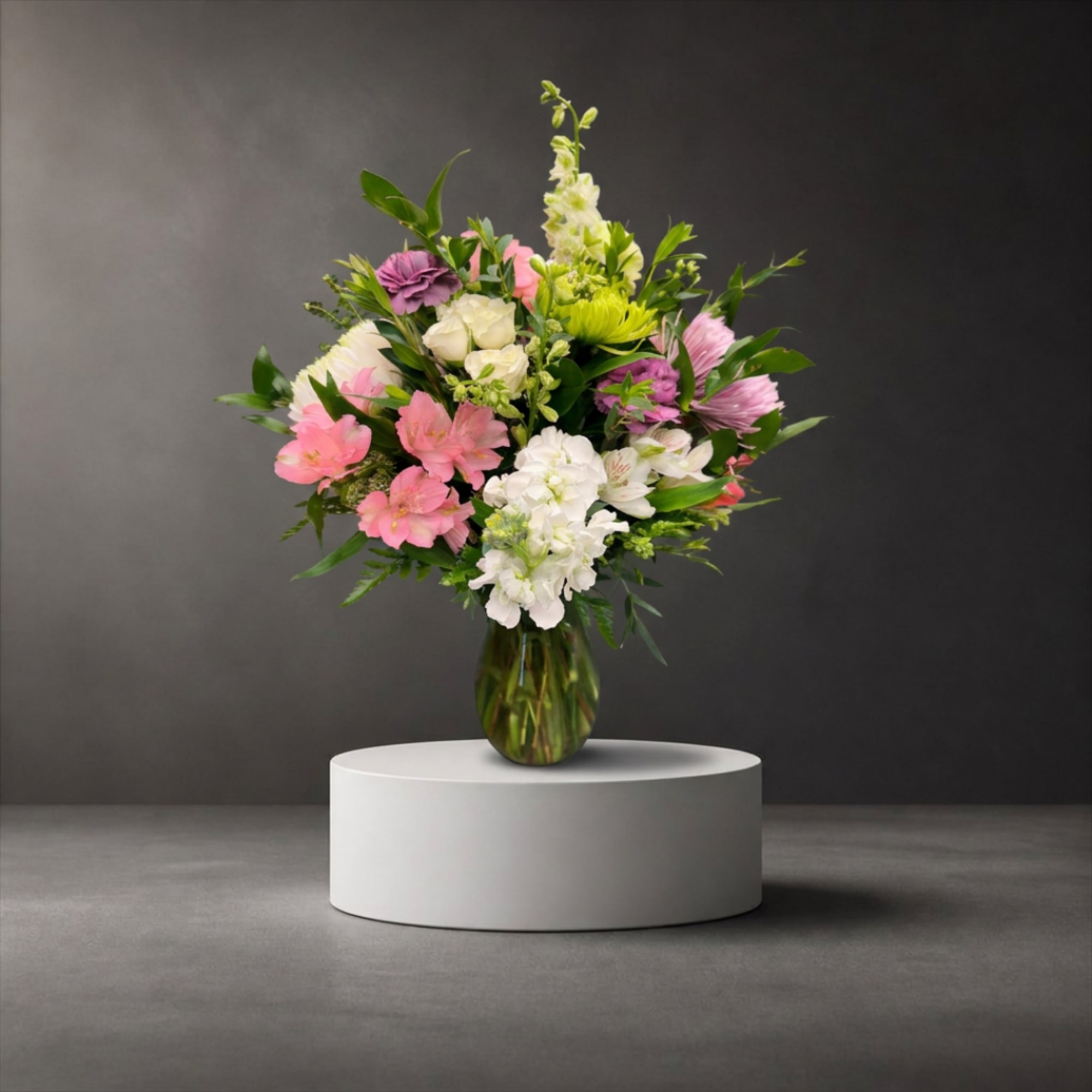 Mixed pink, white, and purple flowers in a glass vase