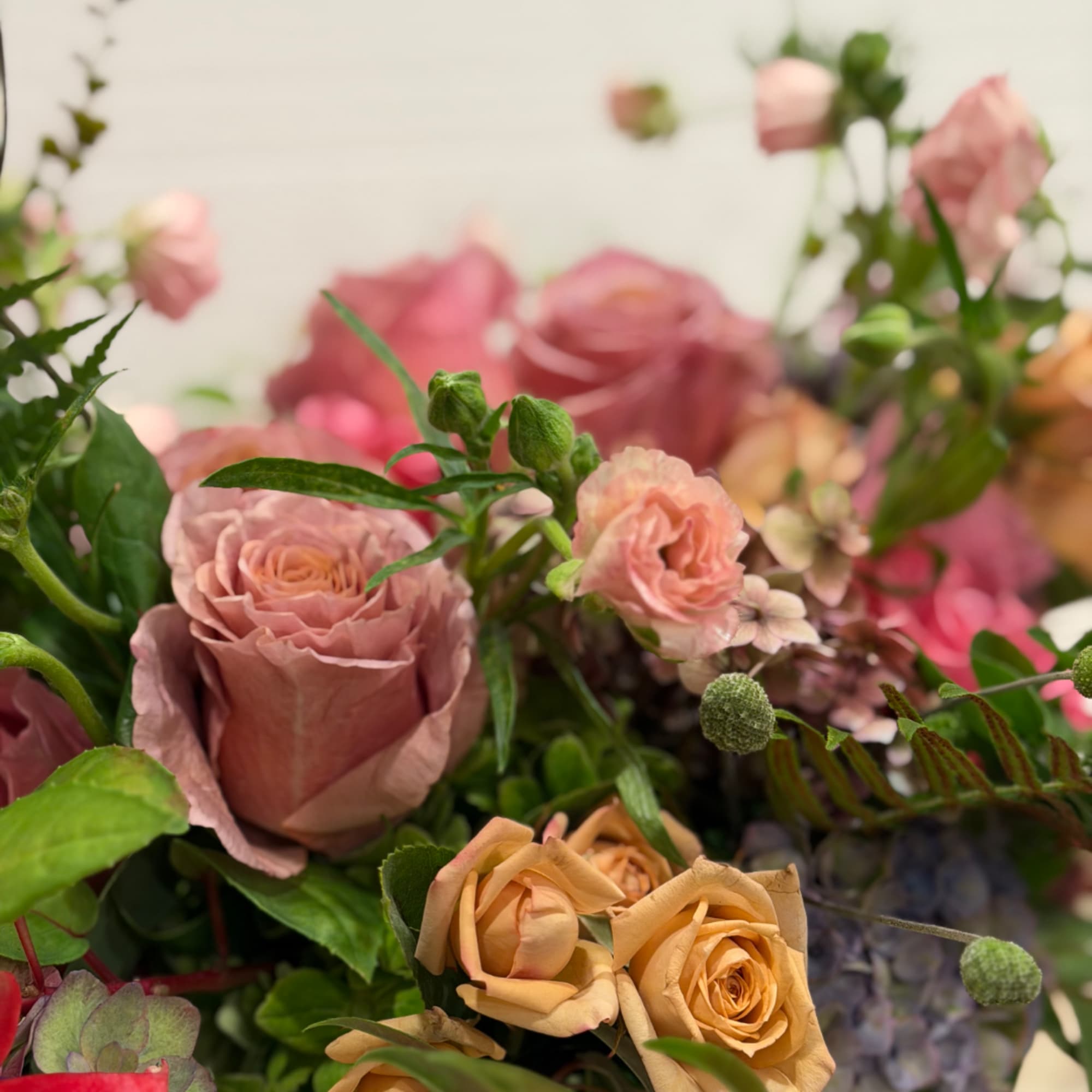 Pink and peach roses with mixed greenery in a bouquet
