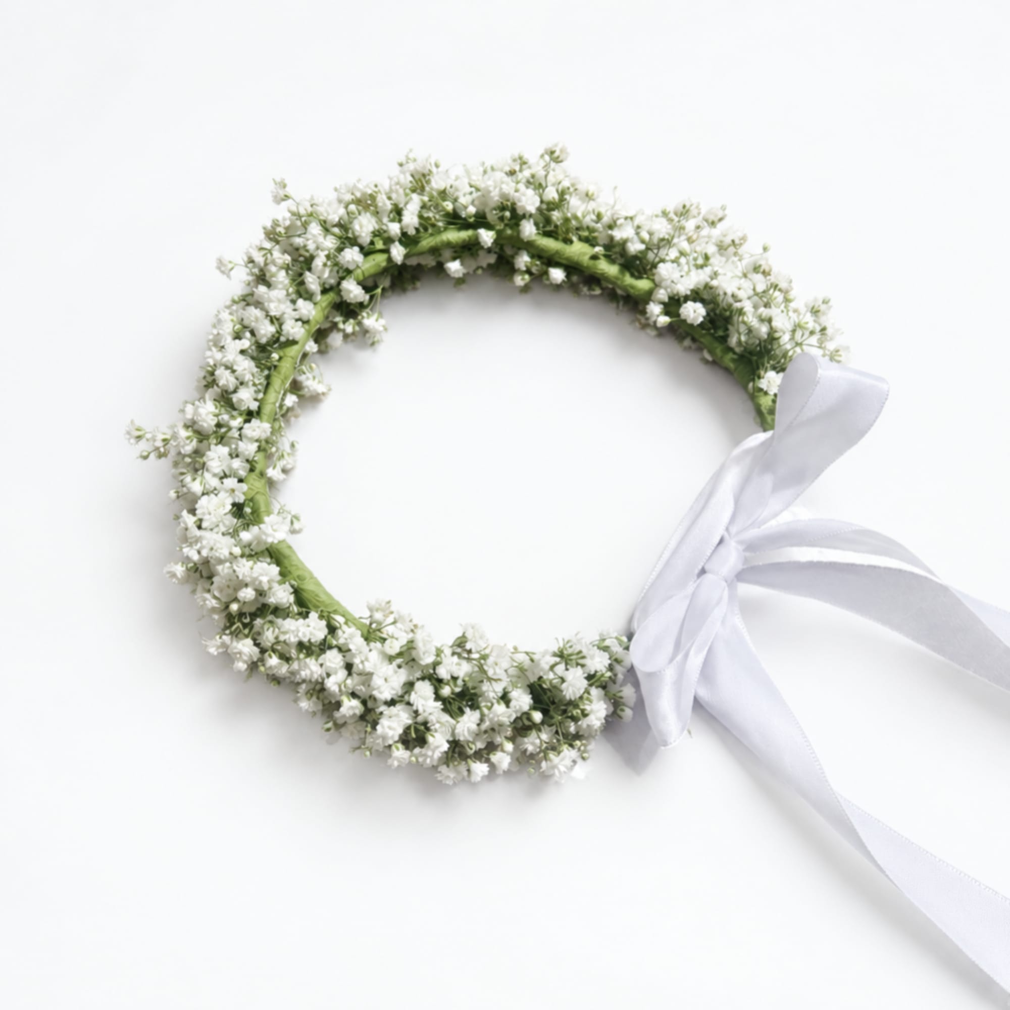 White flower crown with a ribbon tie on a plain background