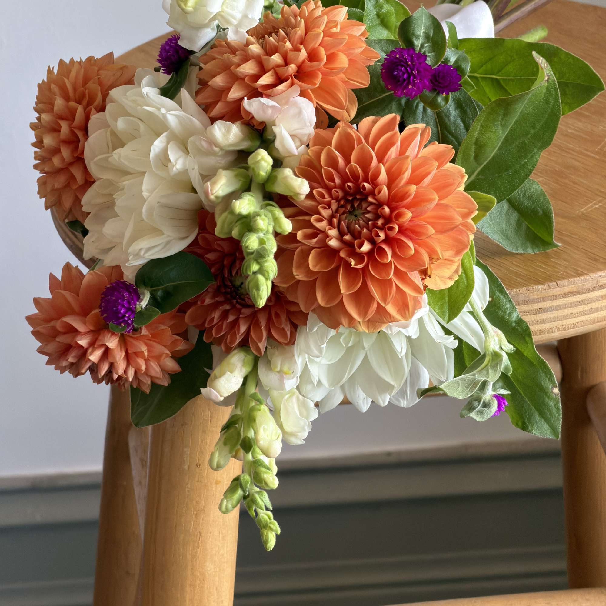 Bouquet of orange and white flowers with green leaves on a wooden chair