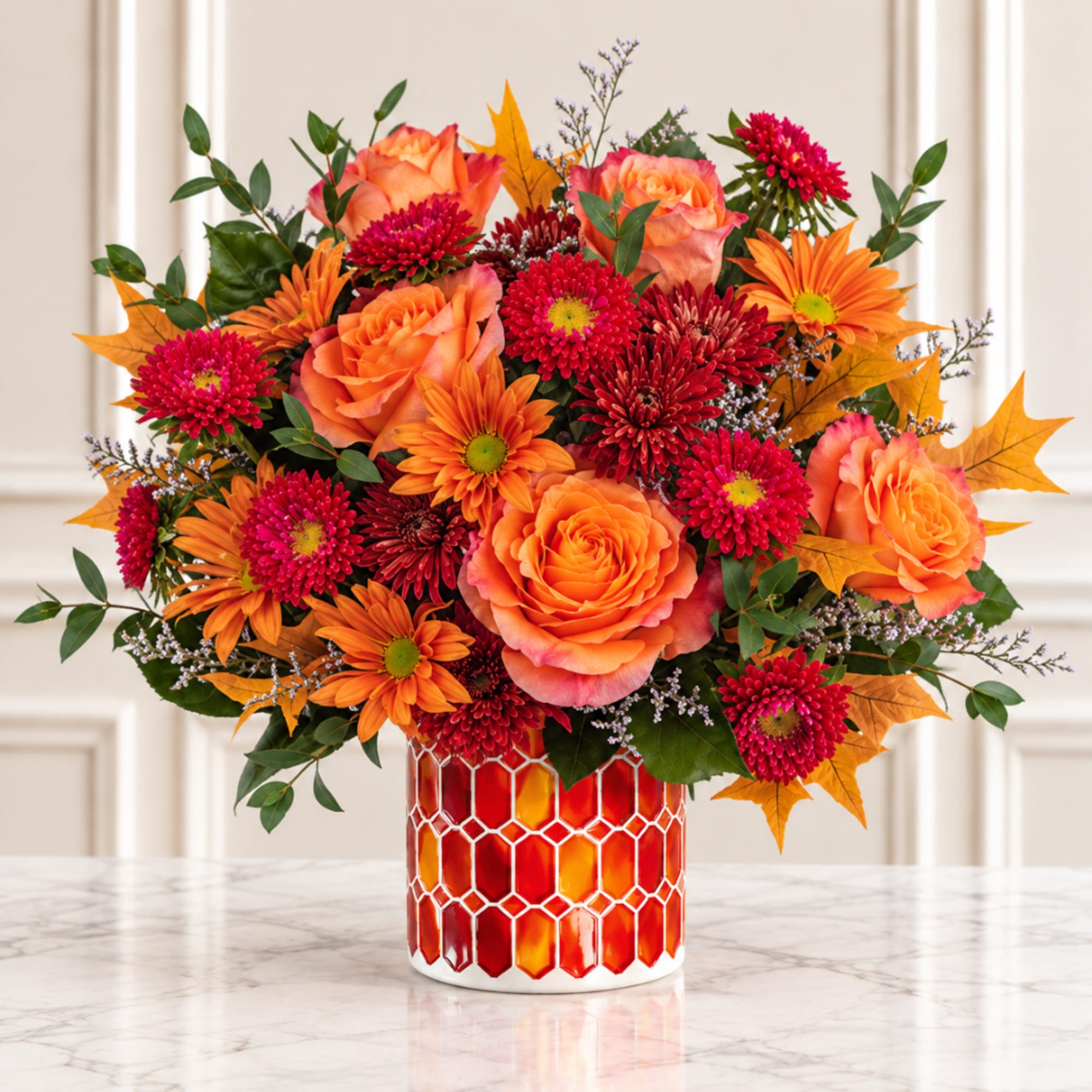 Orange roses and red-orange daisies in a patterned vase